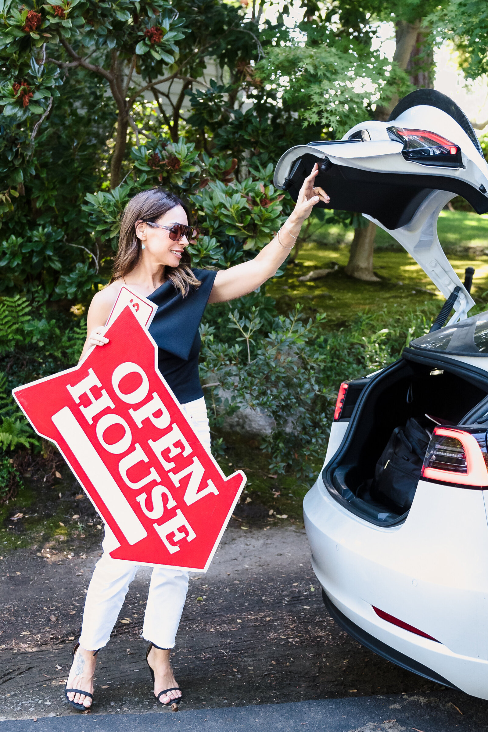 realtor closing the truck and holding an Open House sign