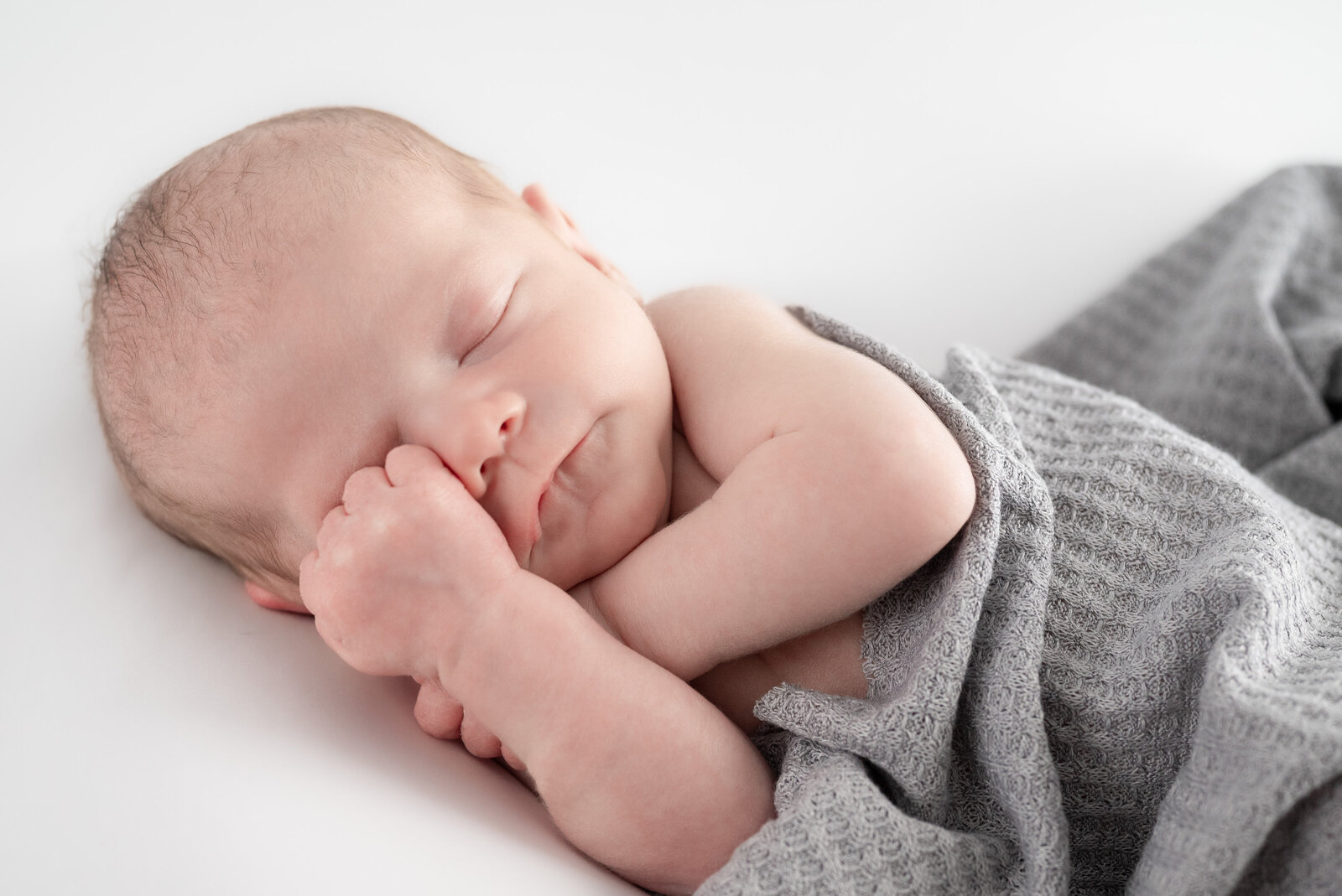 A newborn baby sleeping on his side during  a photo session in Huntsville Alabama studio