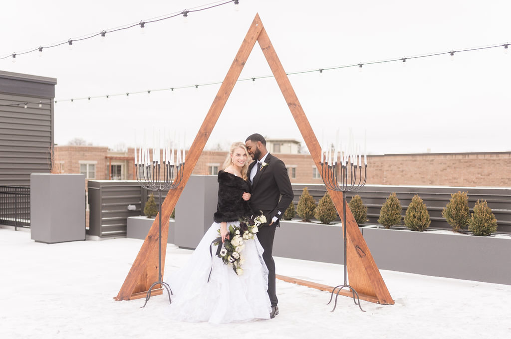 Bride and groom on a rooftop under triangle arch