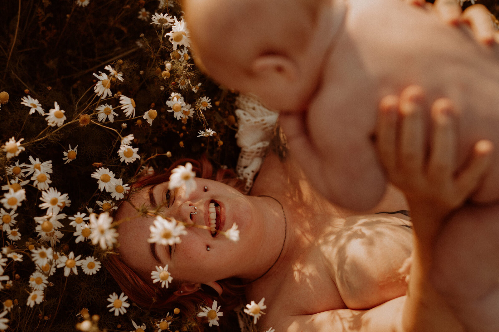 en naken mamma ligger på ett blomfält med sin bebis