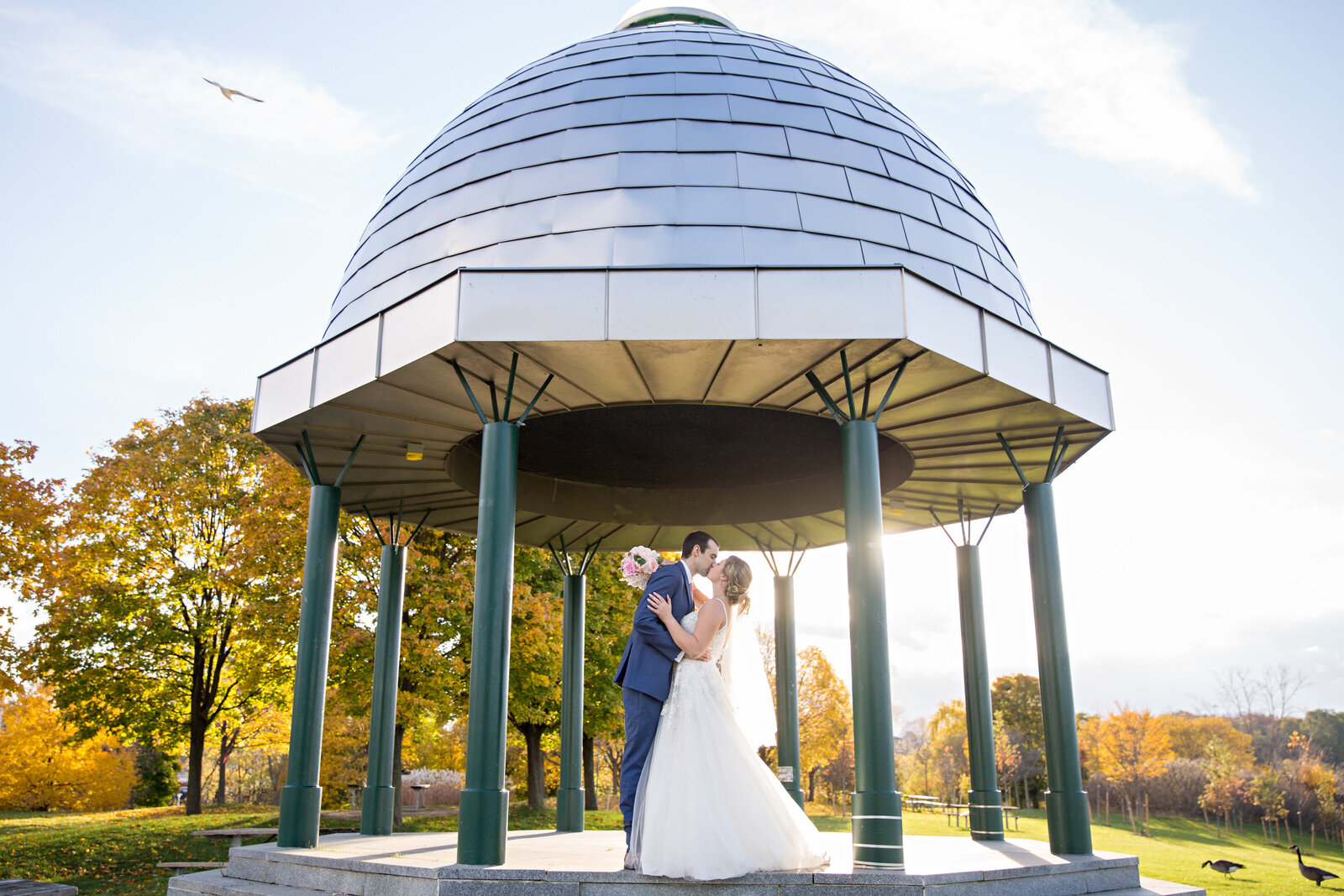 bride and groom kissing under metal gazebo at sunset at Bayfront Park in Hamilton