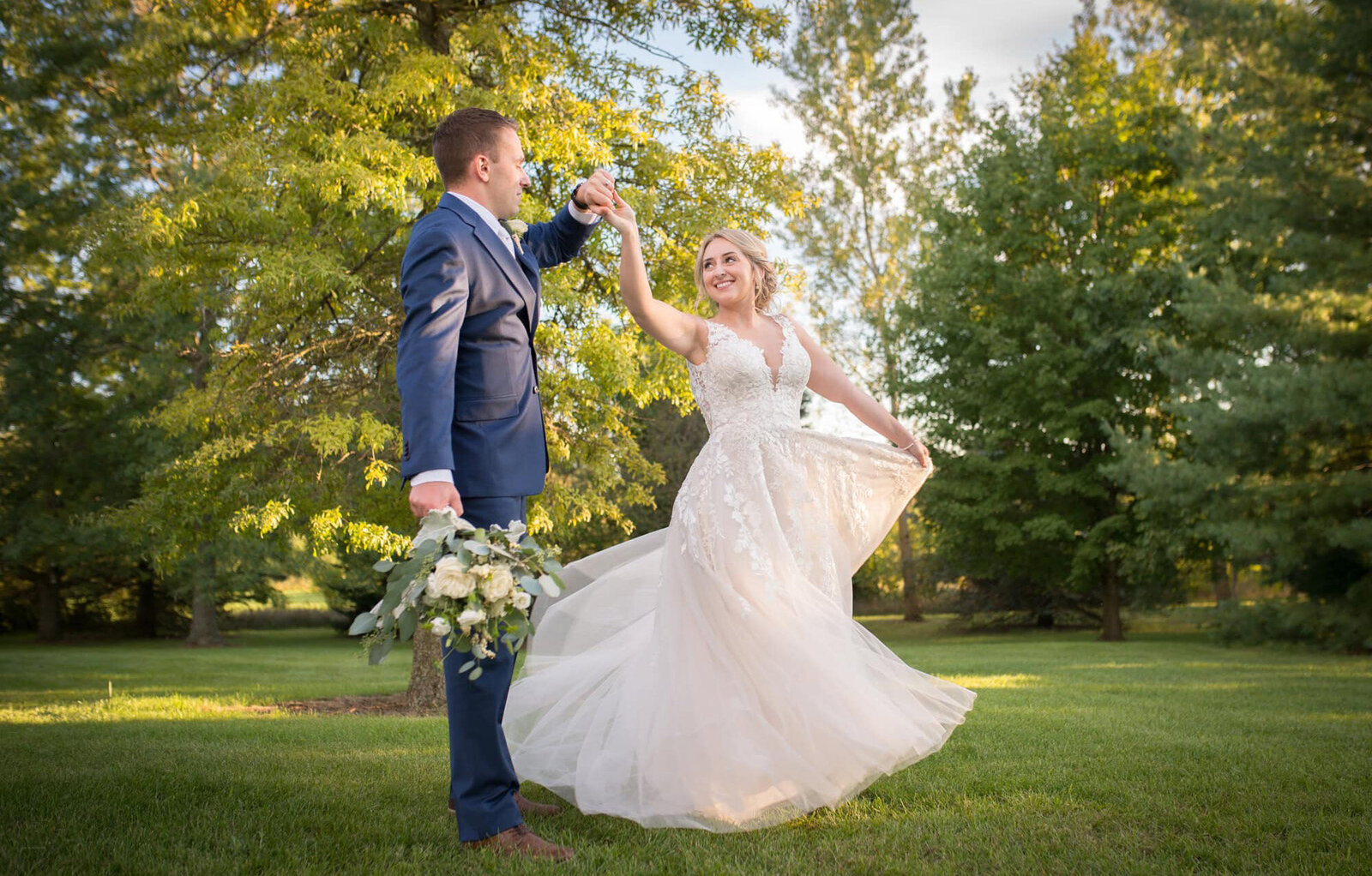 groom twirls bride in wooded backyard