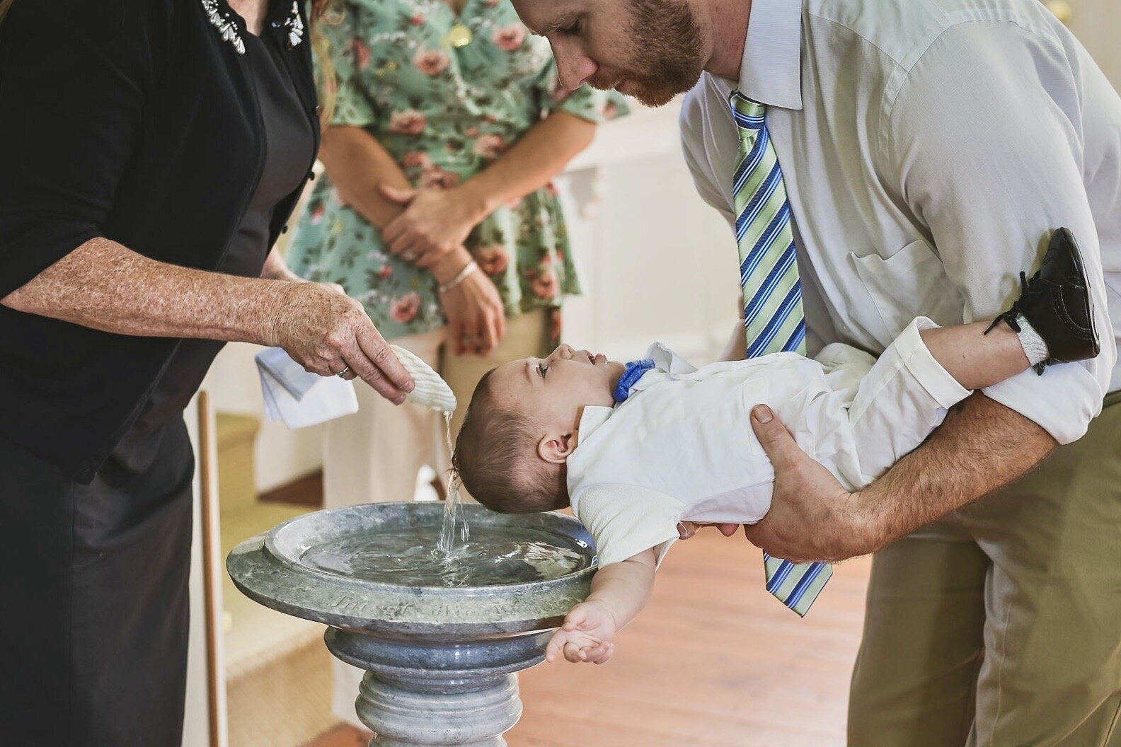 Father holds his baby during baptism ritual