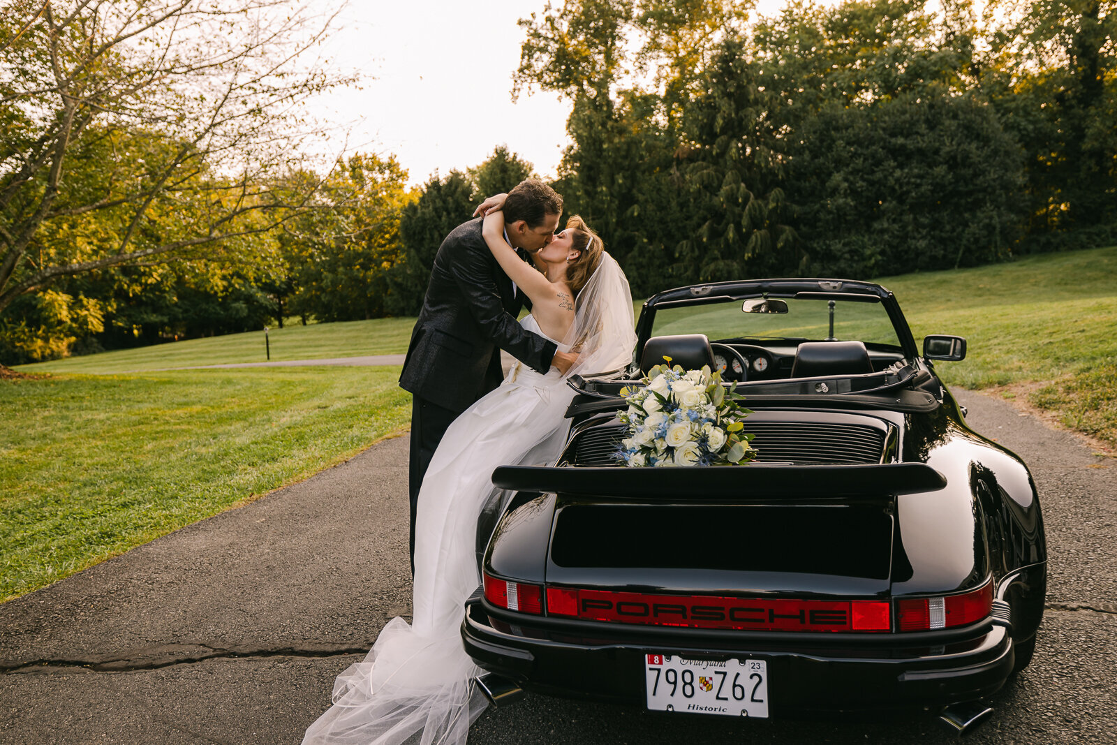Wedding couple sitting on the back of a porsche