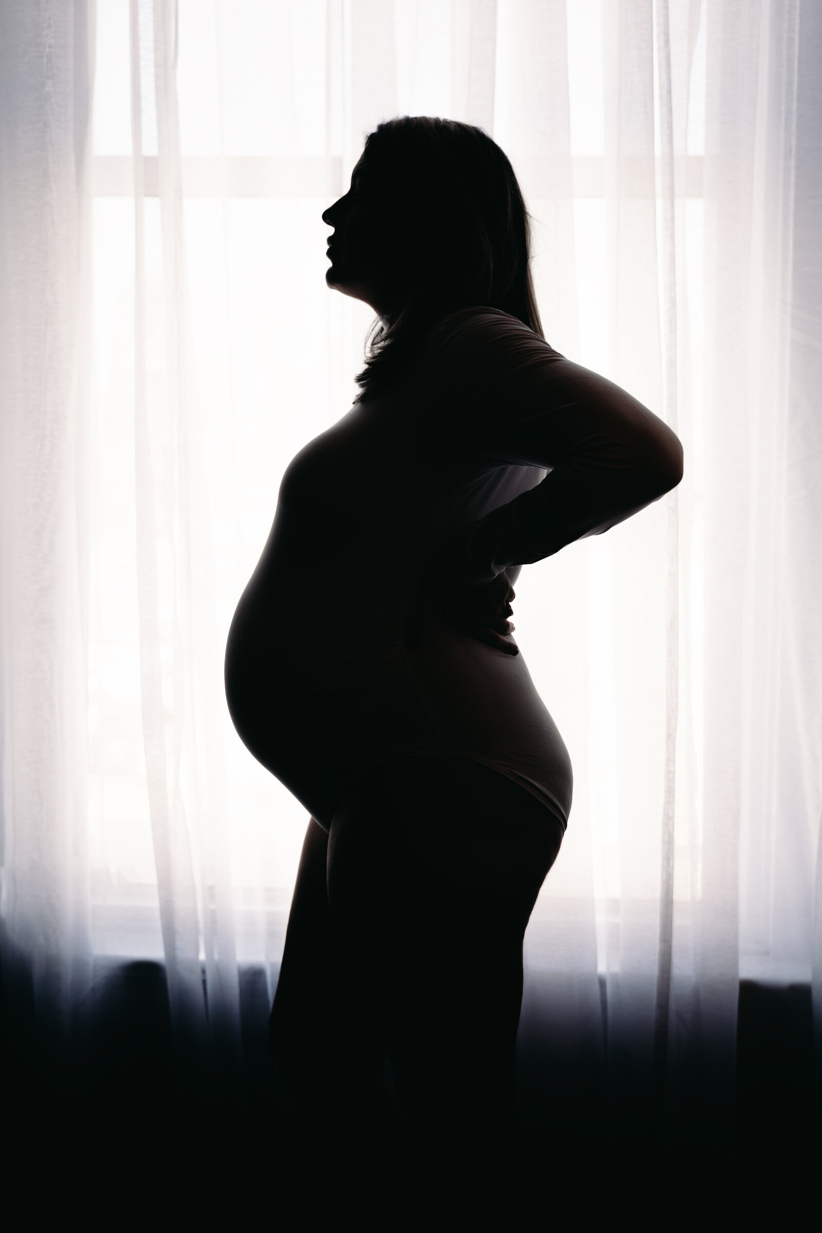 Pregnant woman embracing her belly during a boudoir session in Kansas City
