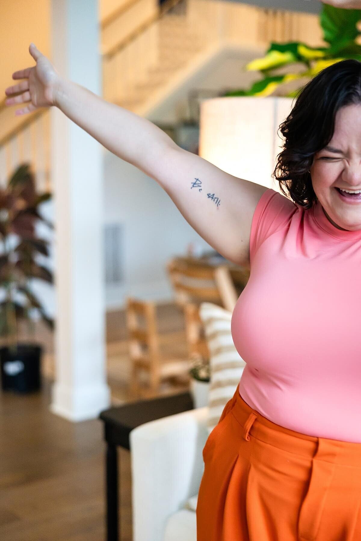 Cropped image of a joyful woman raising her arm in celebration, wearing bright pink and orange during a Seattle branding photoshoot. A lively example of what branding photography looks like when it captures personality, emotion, and fire—ideal for those searching 'brand photographer near me' or 'she plays with fire' style branding.