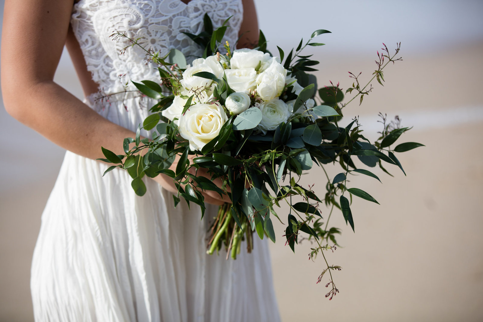 The bouquet is held by the bride in stunning beach engagement session