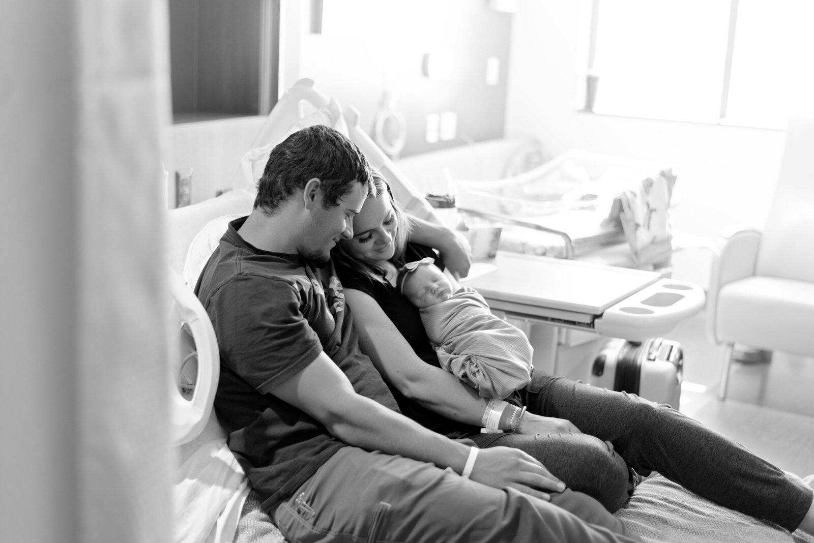 family on hospital bed holding newborn baby
