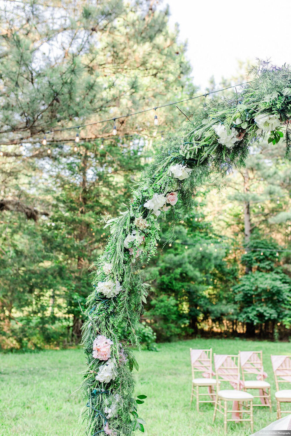 Floral arch with greenery and white flowers in an outdoor setting