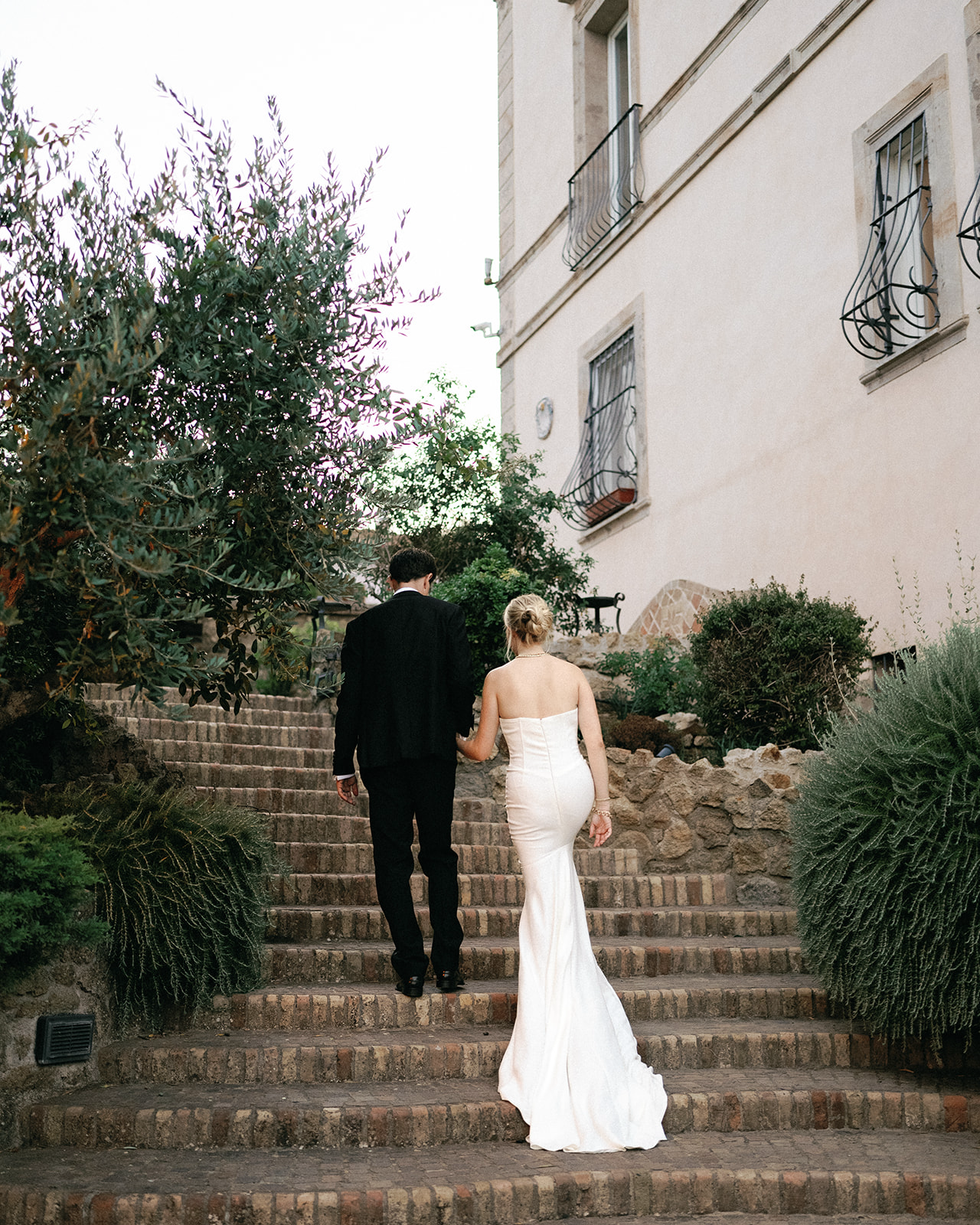 Bride and groom walking carefully up the stairs after their wedding and heading to their wedding reception | Megan Smith Photography