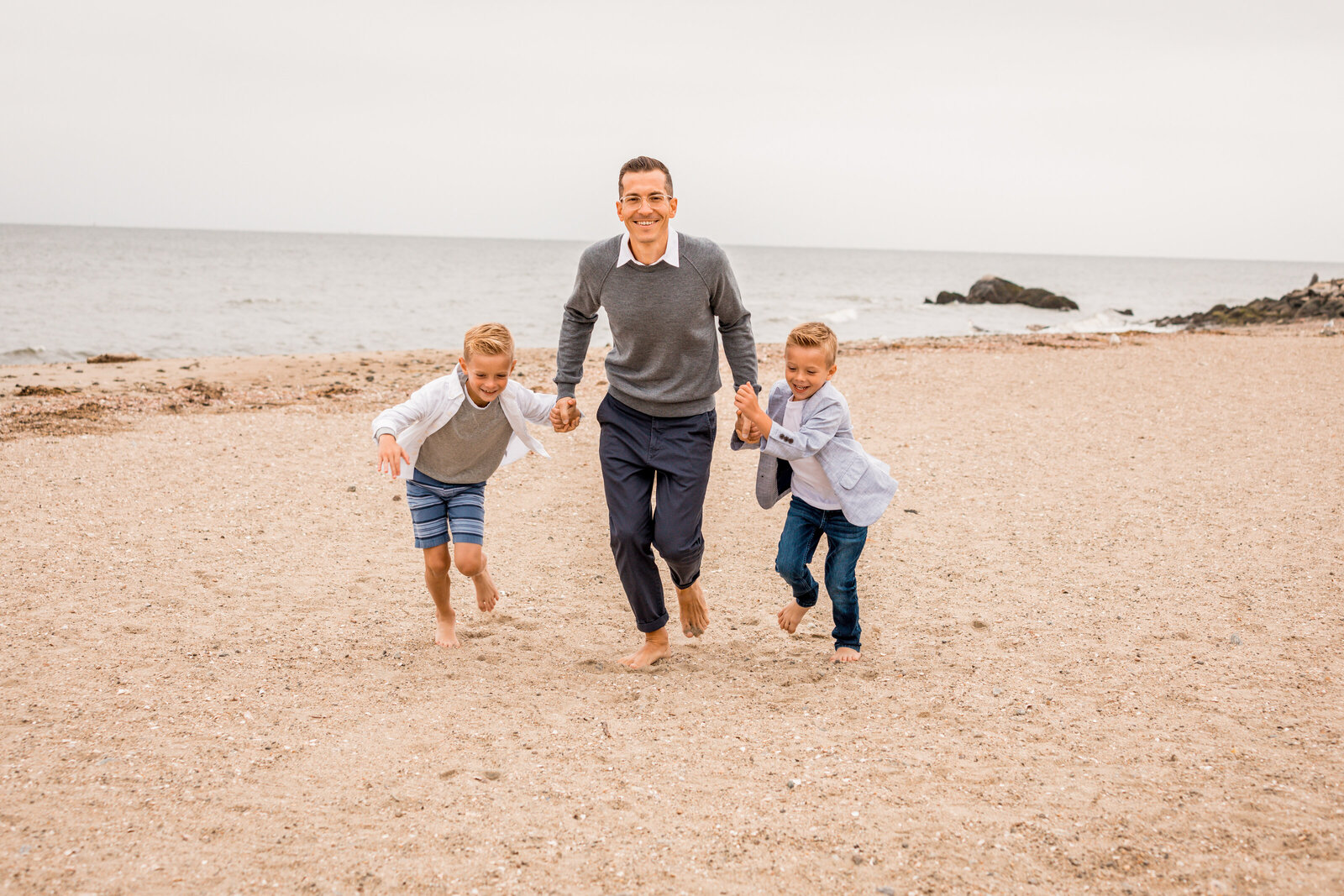 dad is running with his boys on the beach