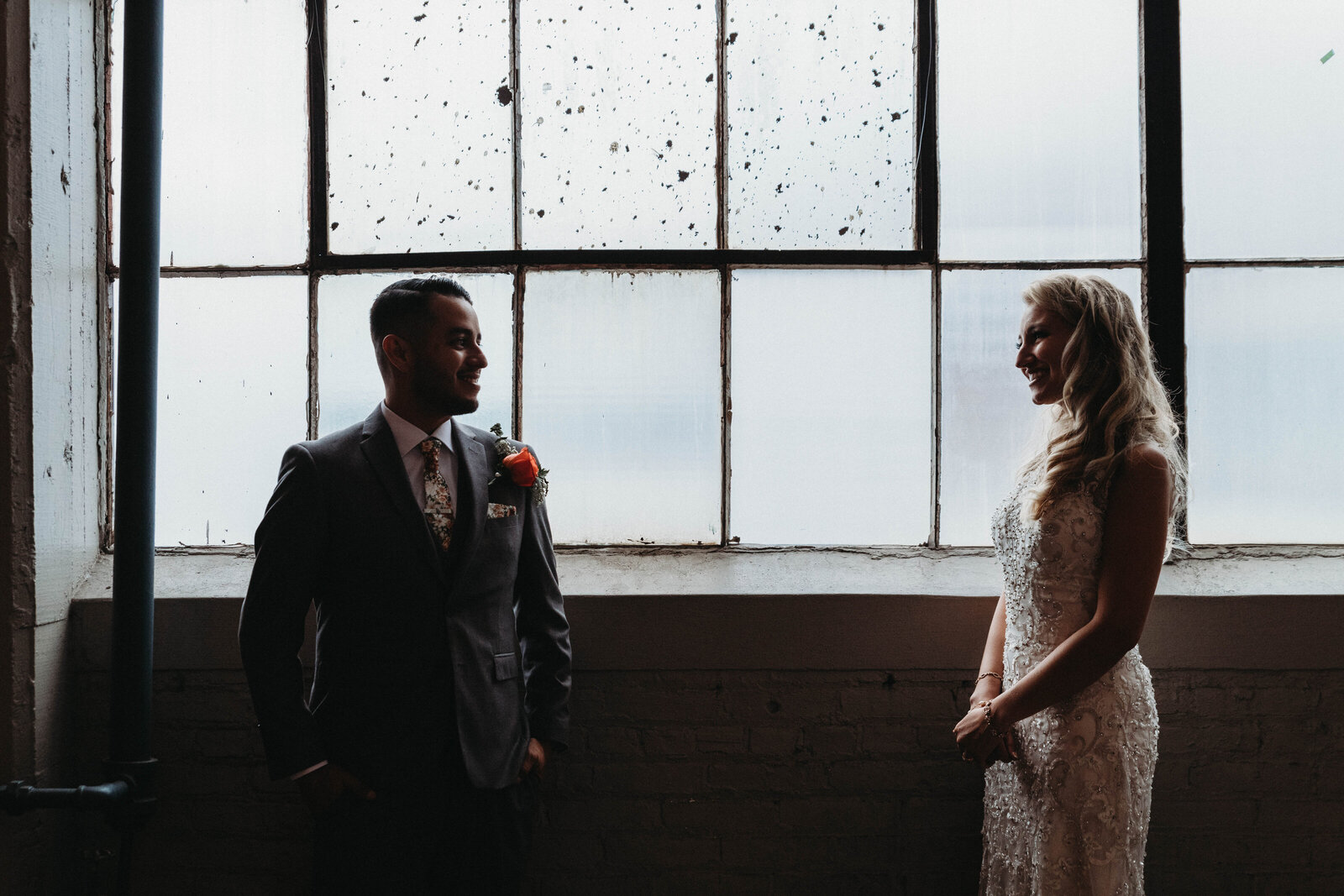 Bride and Groom stand in front of window at Lake Erie building/Screw Factory at wedding day.