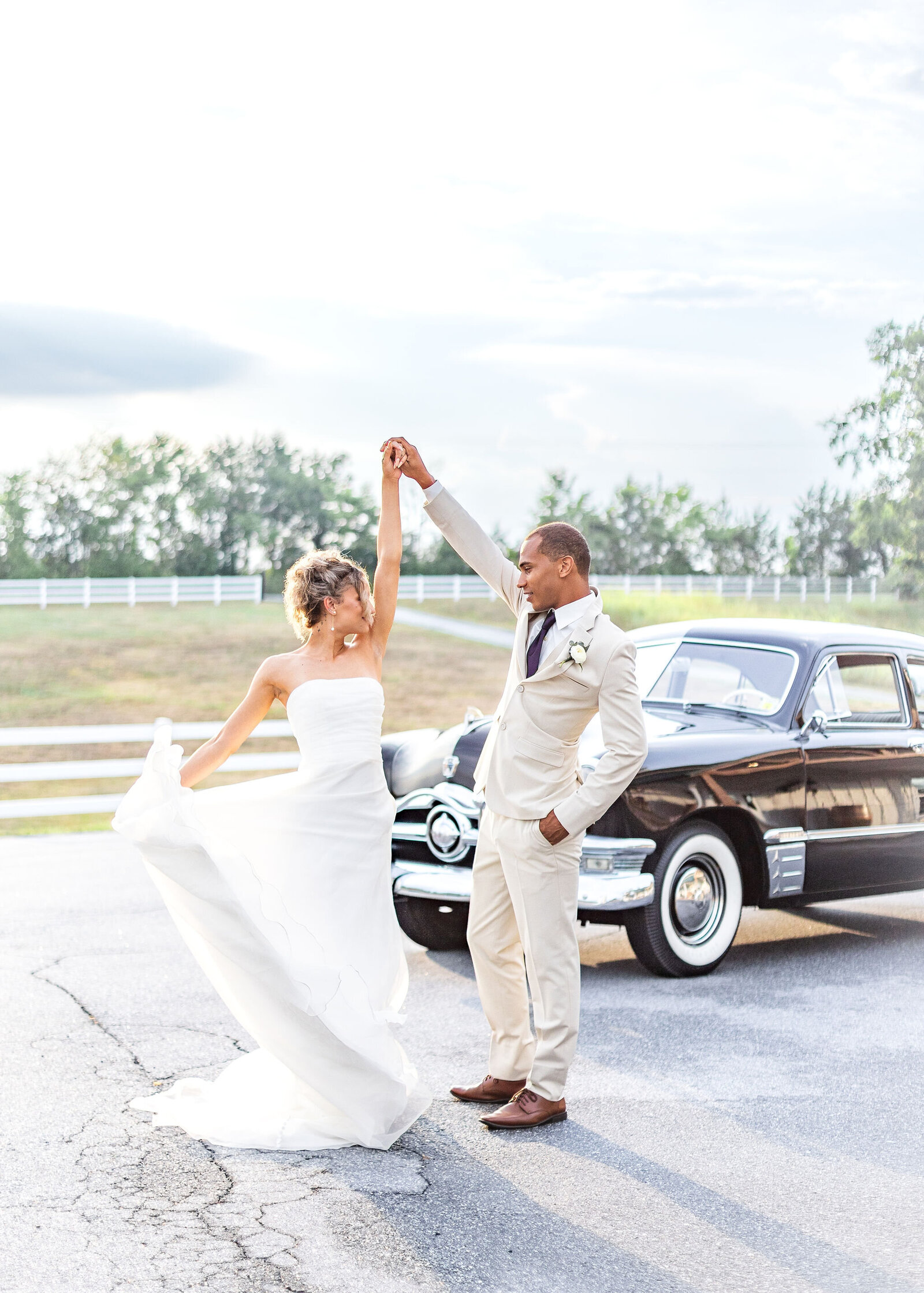 Bride and groom dancing near a vintage car on the grounds of Willow and Stone Events, surrounded by beautiful North Carolina countryside.