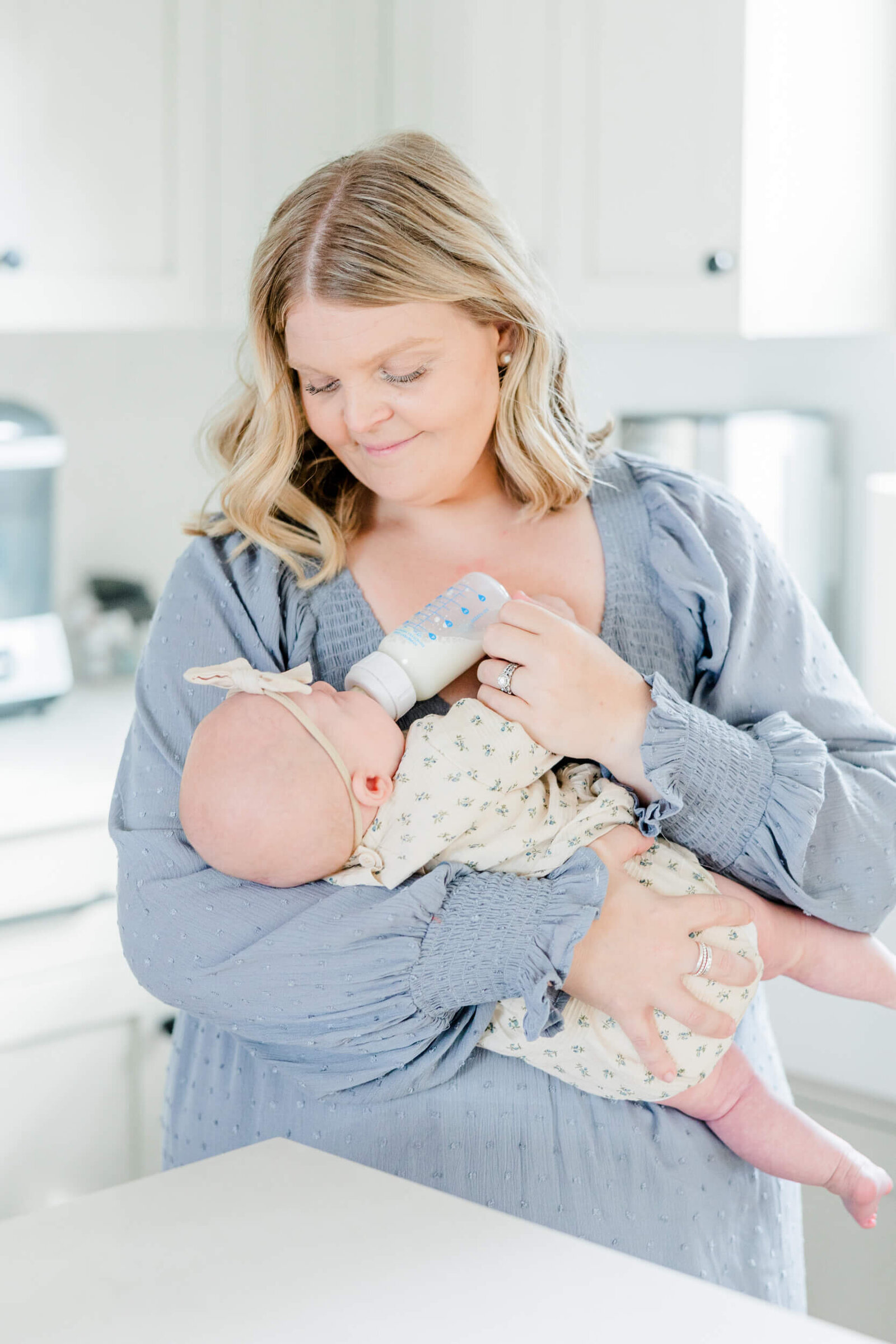 Mom feeds her newborn a bottle in the kitchen