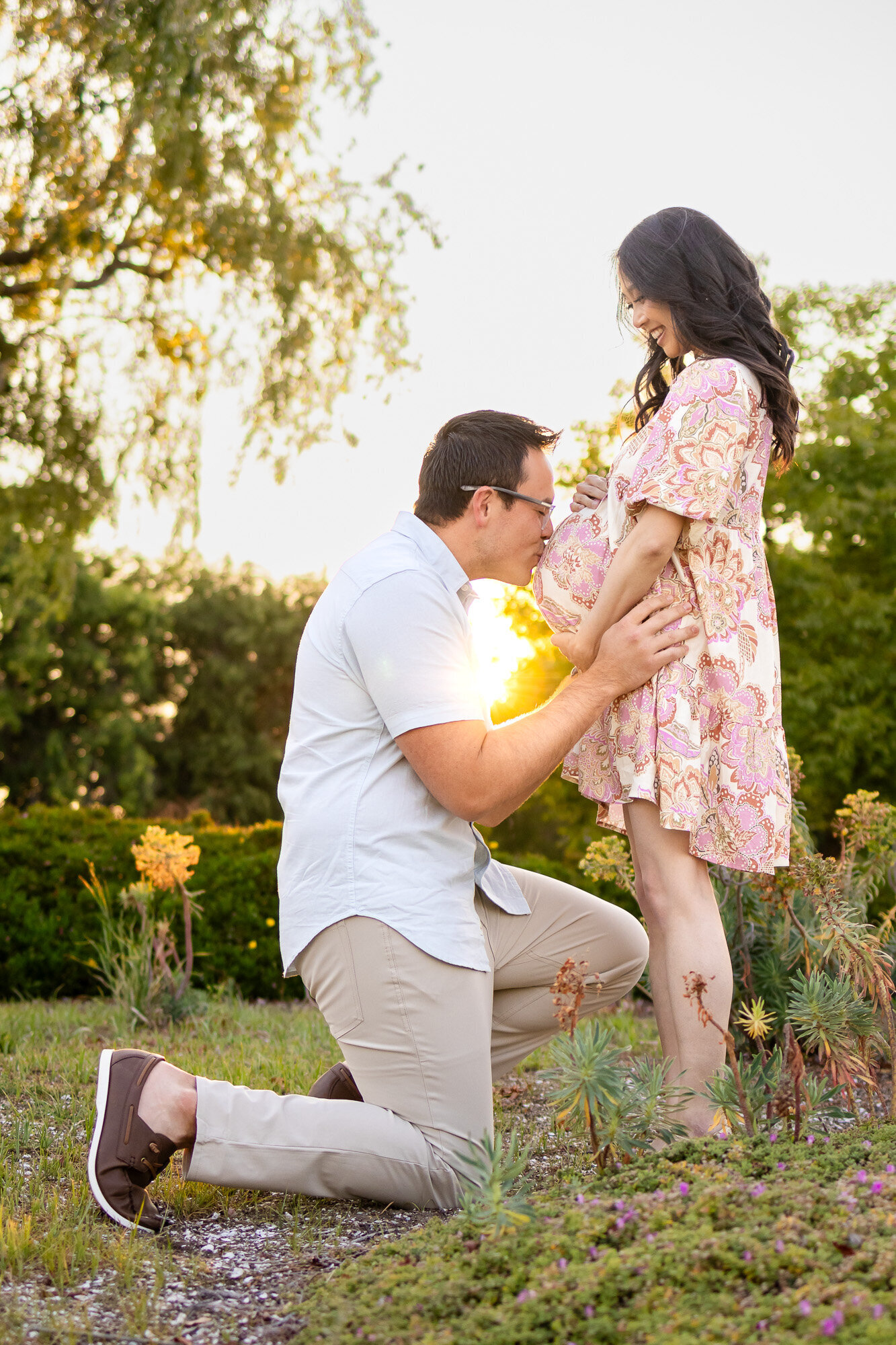 Golden hour maternity session with couple embracing in nature, captured by Ellobelle Photography in a joyful, light-filled moment.