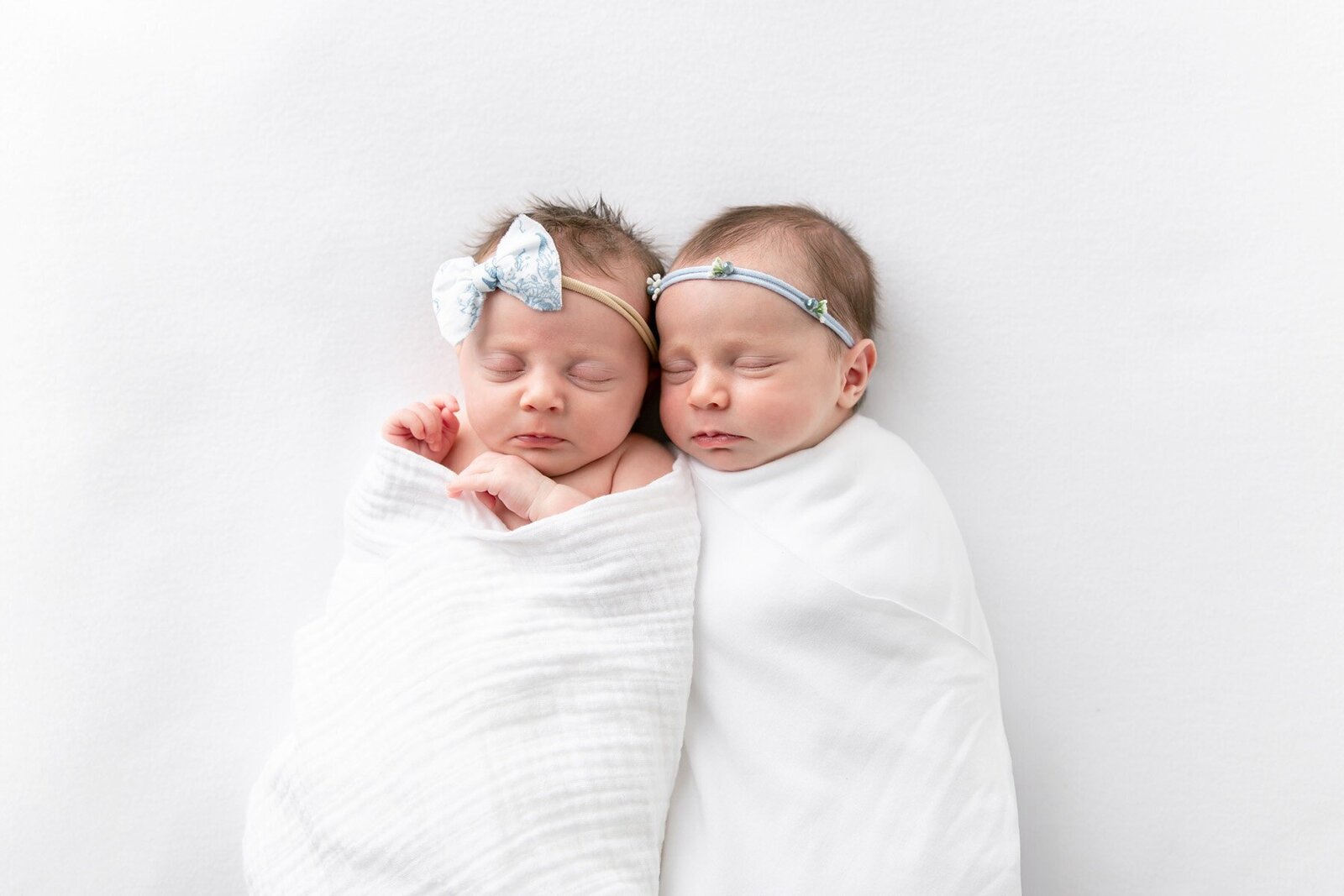 Twin newborns swaddled together wearing headbands to show newborn photography savannah