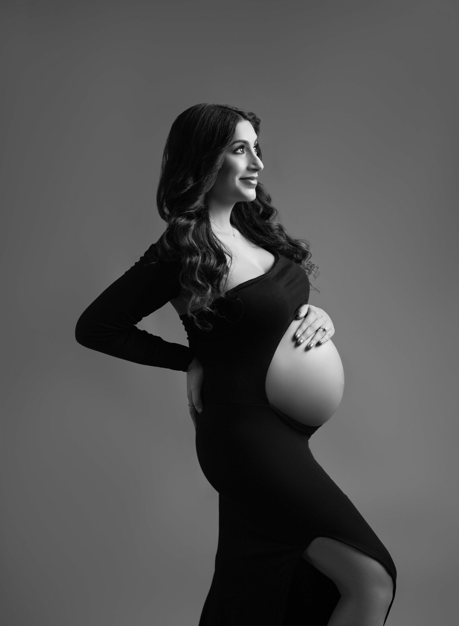 Pregnant women in black maternity dress with baby bump out. Professional portrait taken at Atlanta Photo Studio.