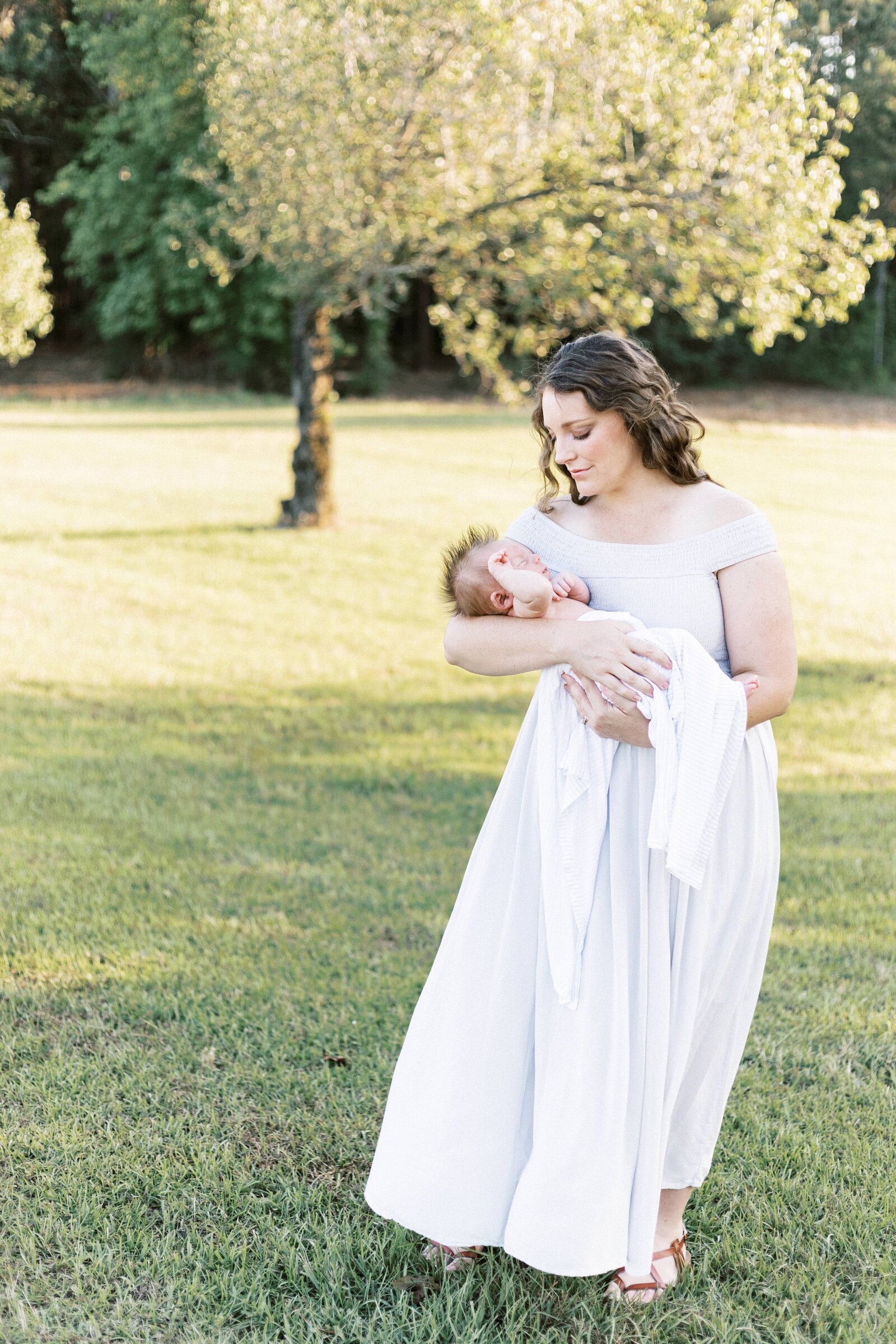 mom standing outside and smiling at newborn baby in peoria illinois newborn photos