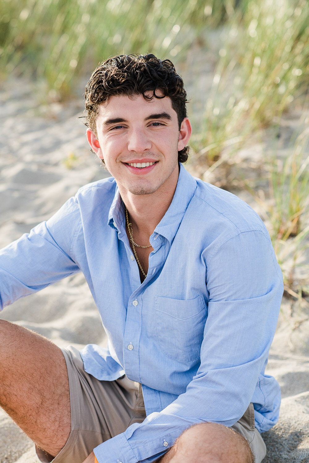 senior boy sitting on sand 