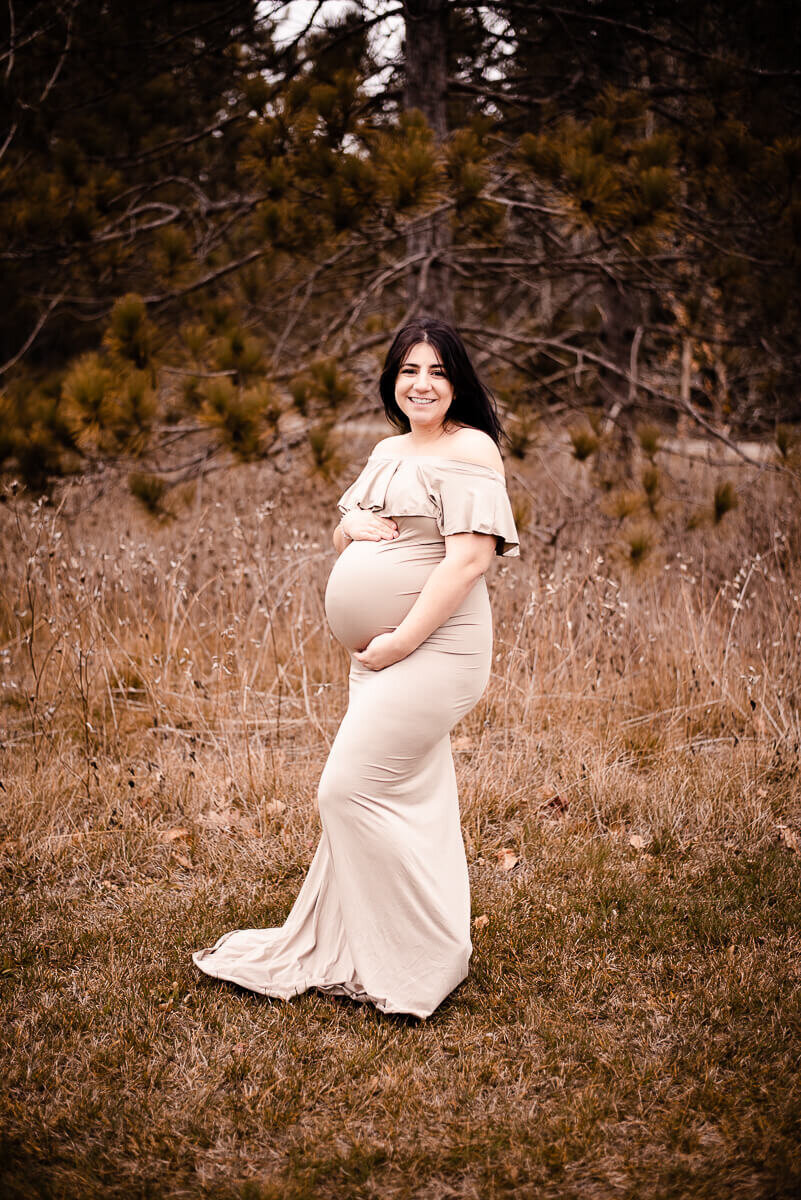 Happy mom posing for Toronto maternity photos in tan gown