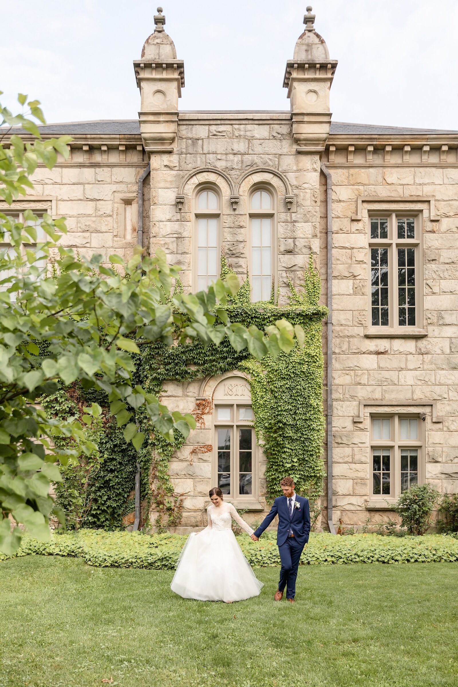 Woodstock-City-Hall-Elopement-Bride-and-Groom-Hold-hands-walking-away-from-castle-like-city-hall