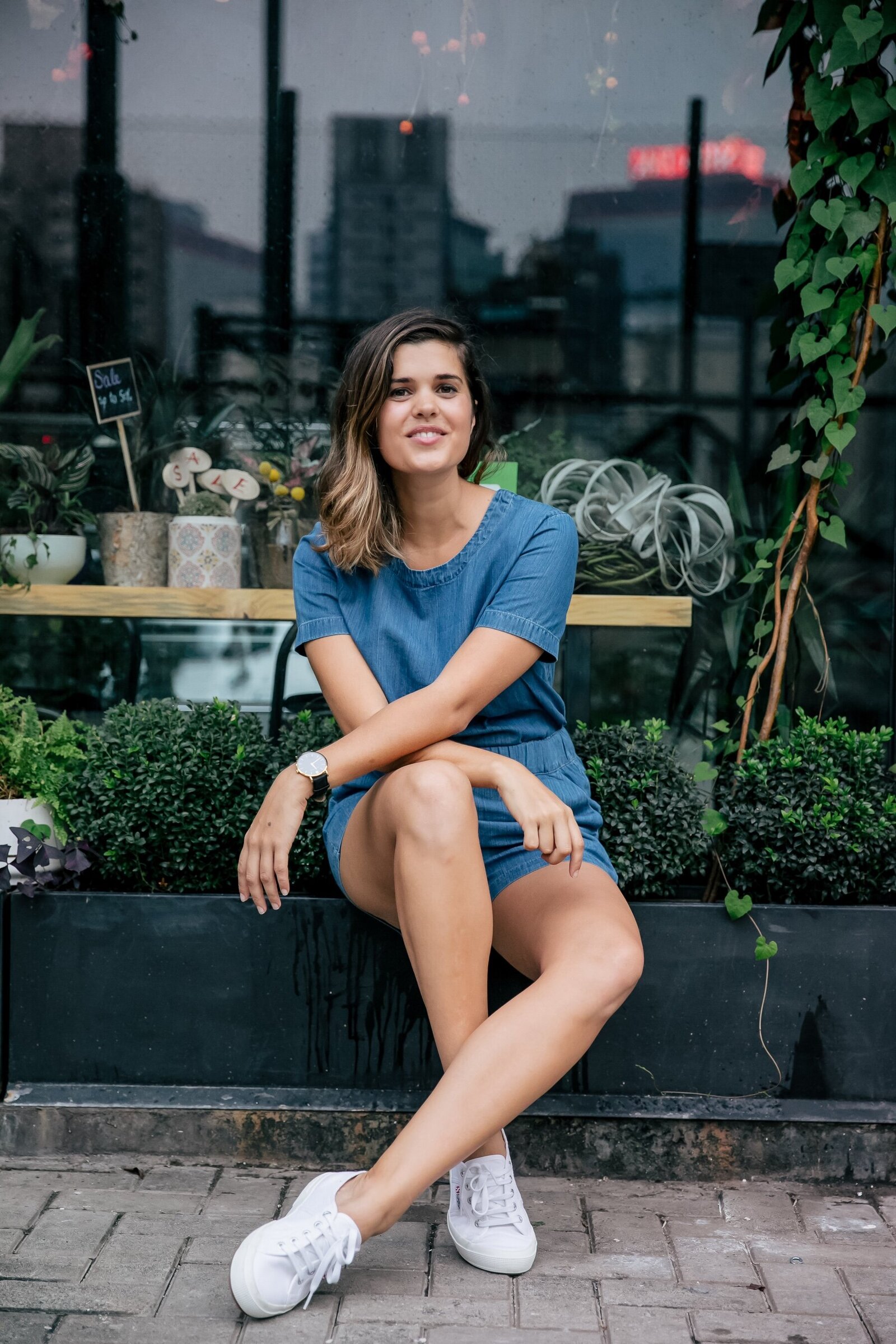 Geneva sitting in front of plants in a denim outfit