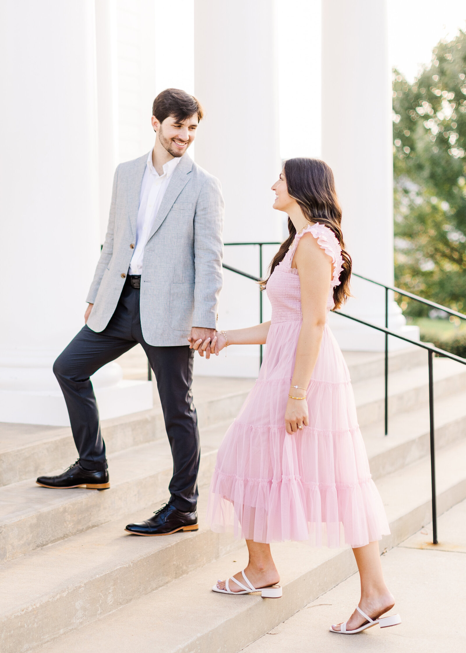 Lauren and Zac holding hands on elegant steps, showcasing their engagement style in Alabama. by Abby Bell Photography, fine art wedding and portrait photographer.