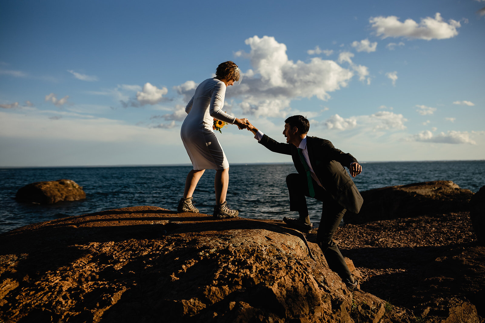 Couple climbs up a rock on the most magical elopement day