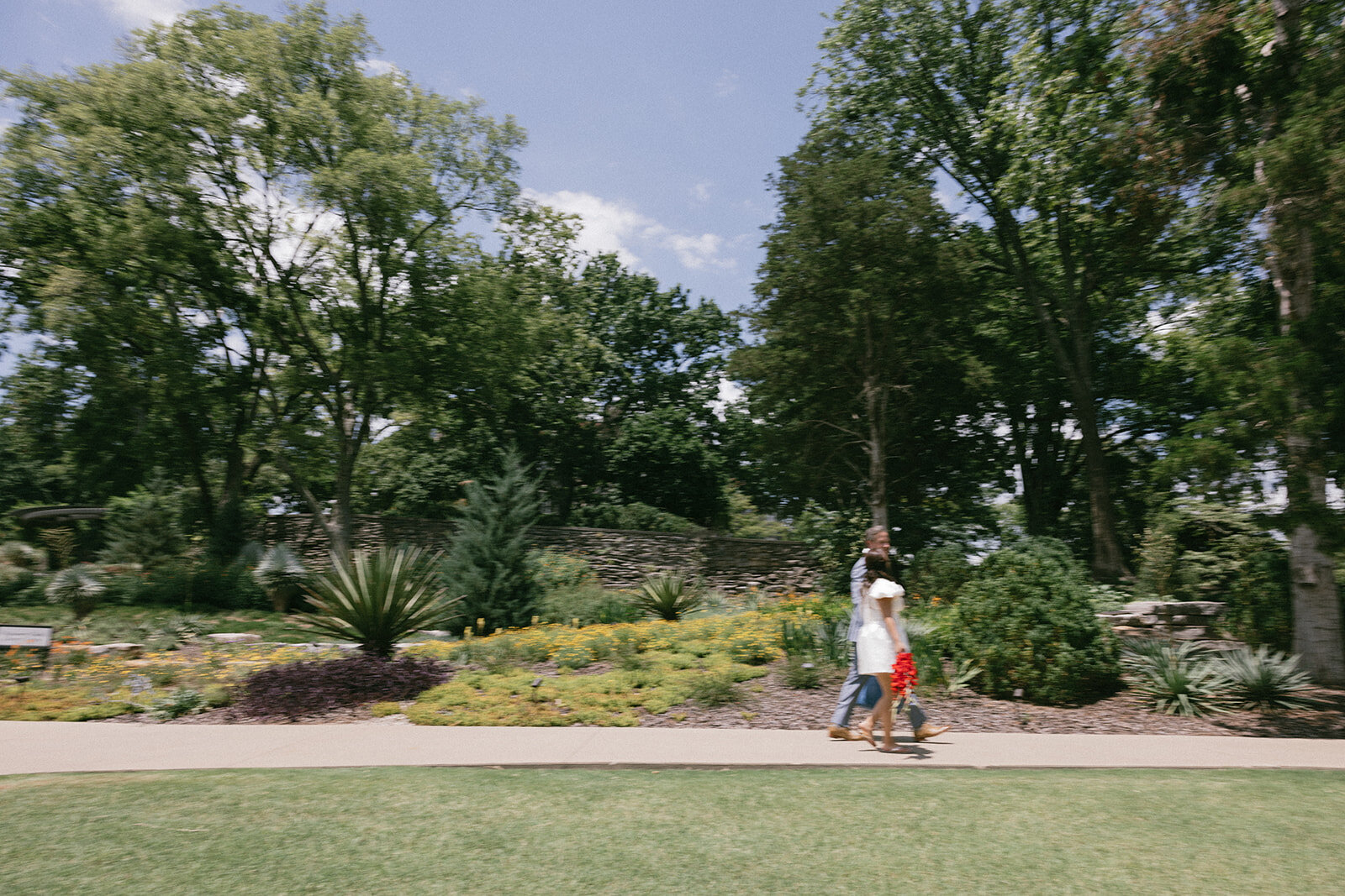 Couple walk past a garden at Cheekwood gardens on their way to elope near the mansion in Nashville, TN.
