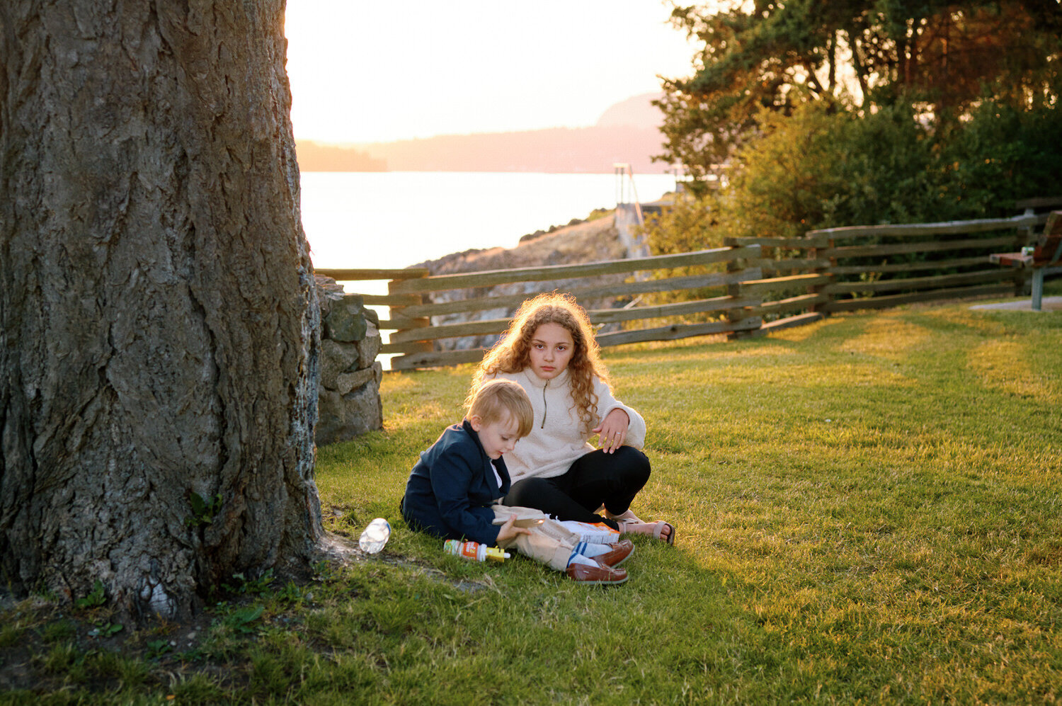 Young wedding guests sit in the sunset light away from the wedding reception