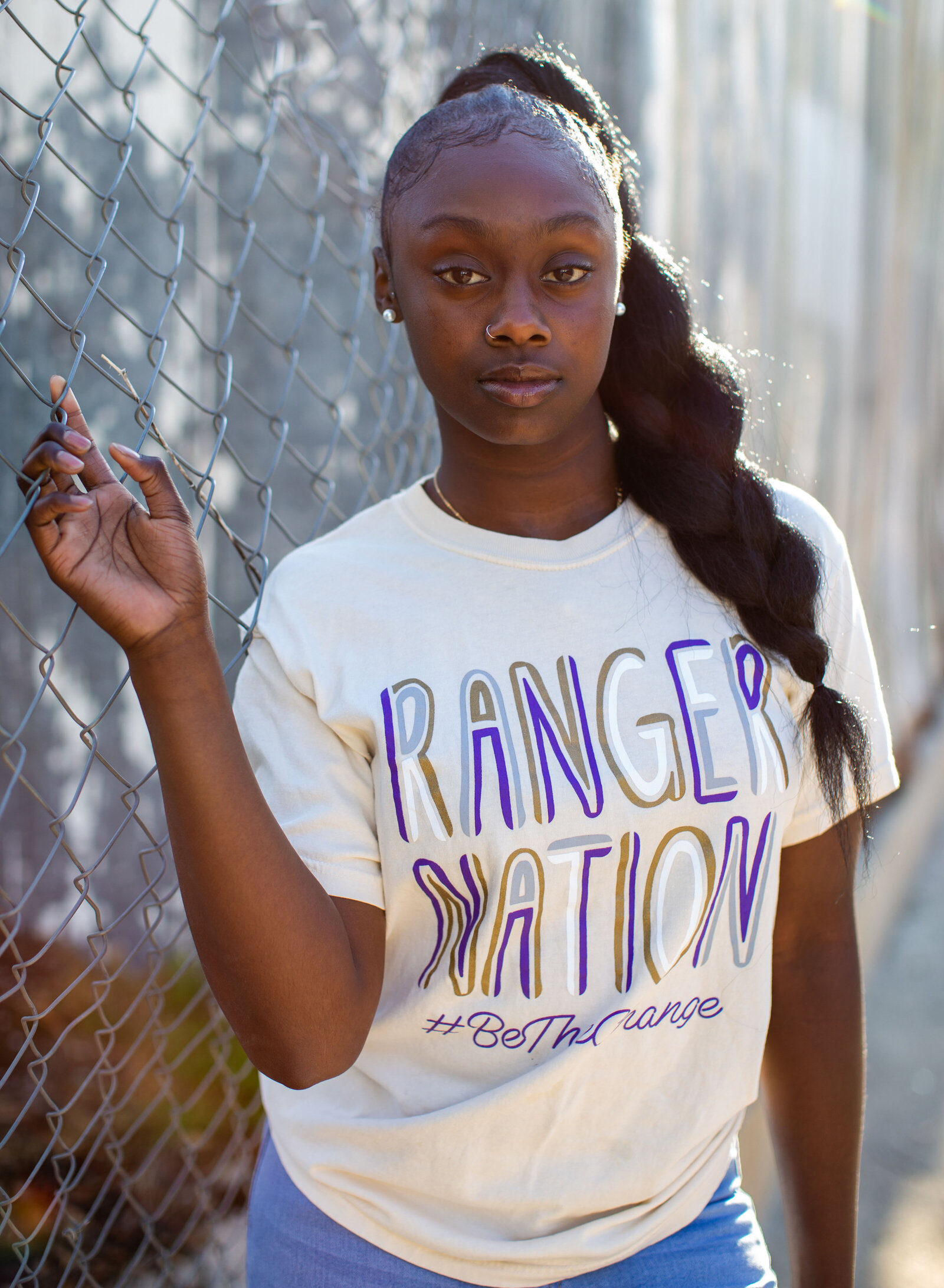 girl posing by chain link fence