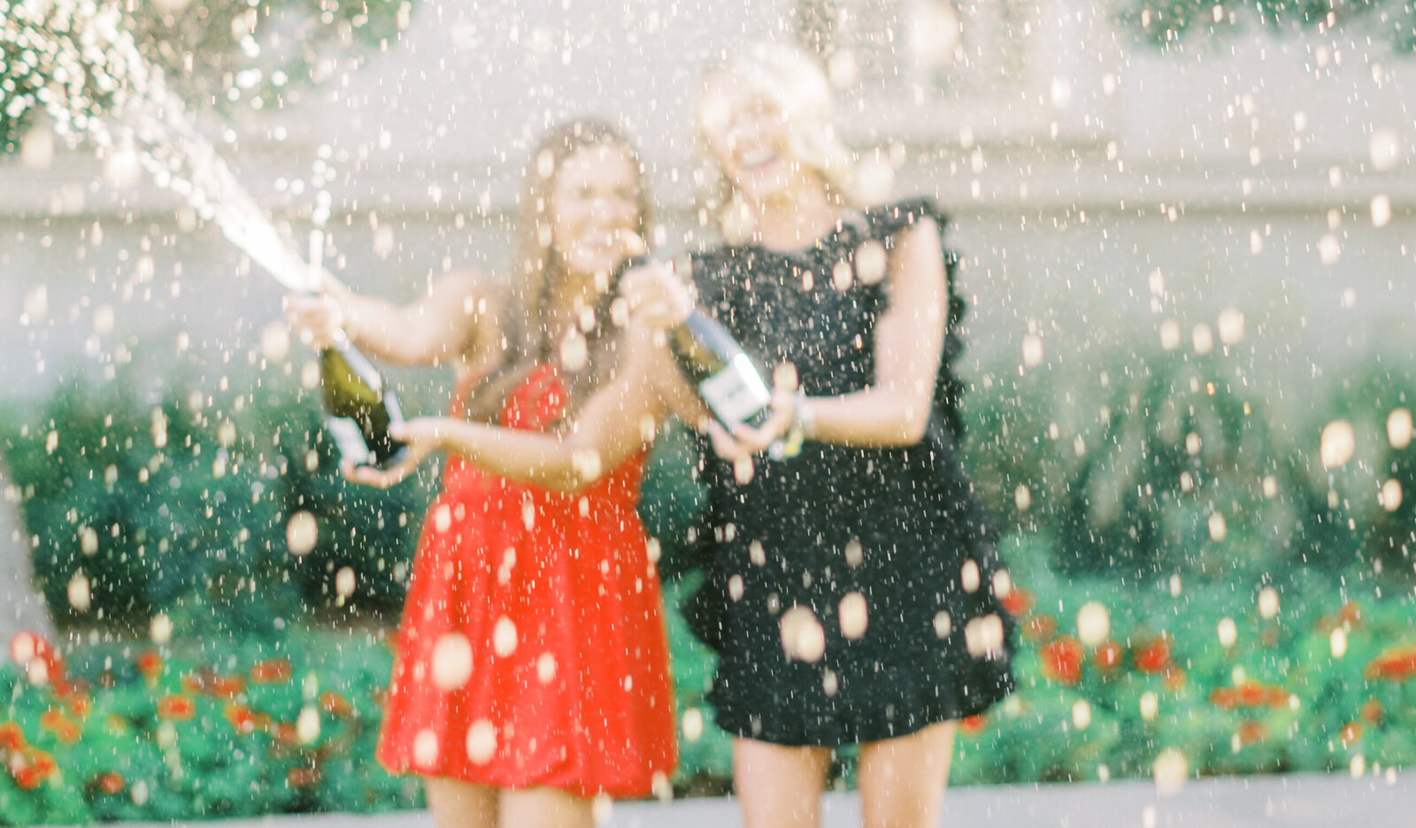 Two college senior girls spraying champagne at the camera