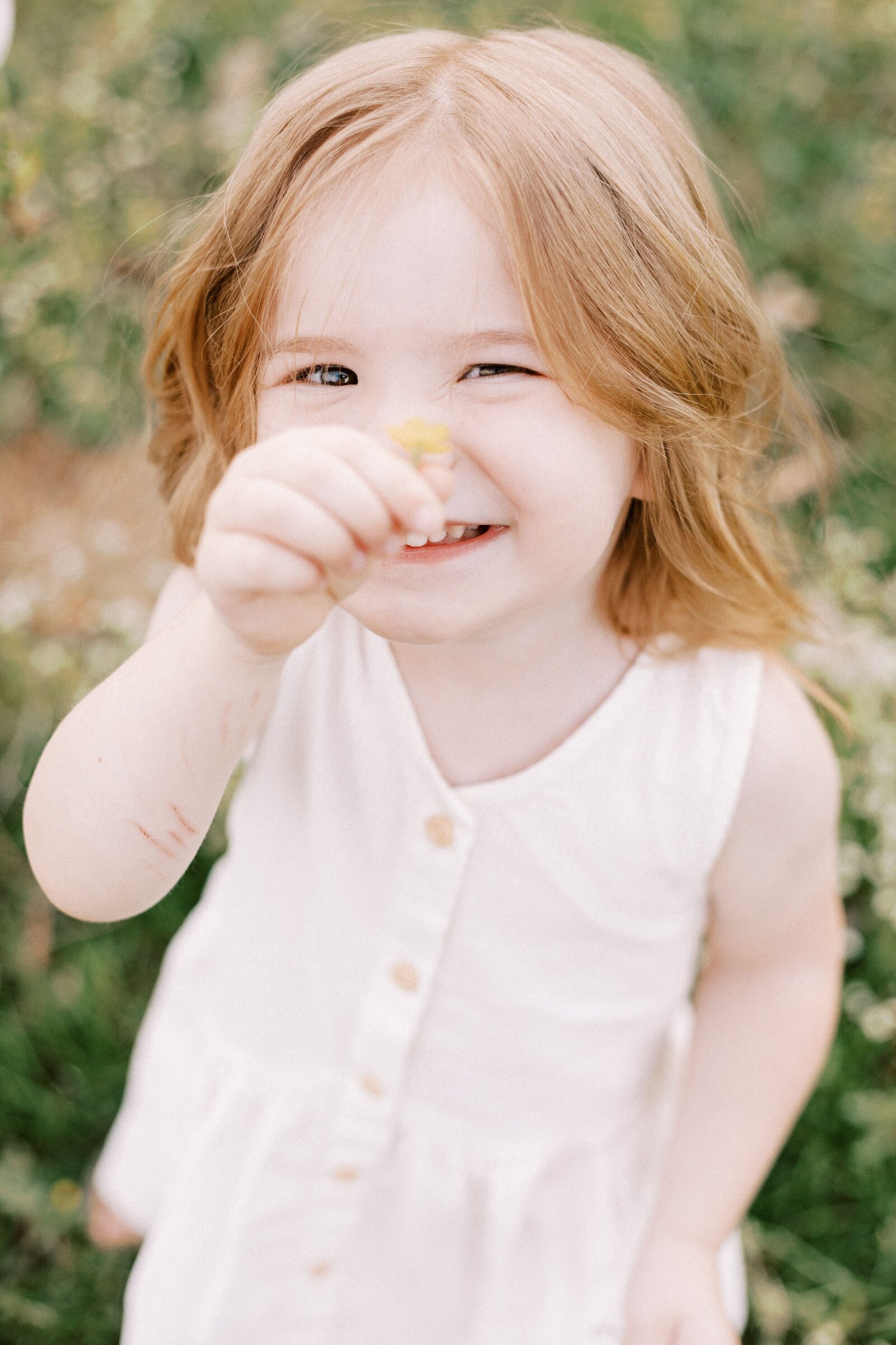 little girl smiling and holding flower during peoria illinois family photos
