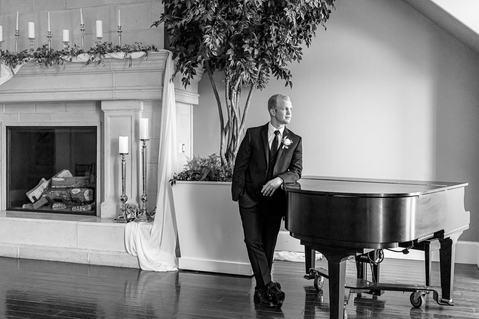 B&W salt lake photography of a groom leaning against a grand piano at the Sleepy Ridge Clubhouse in Orem