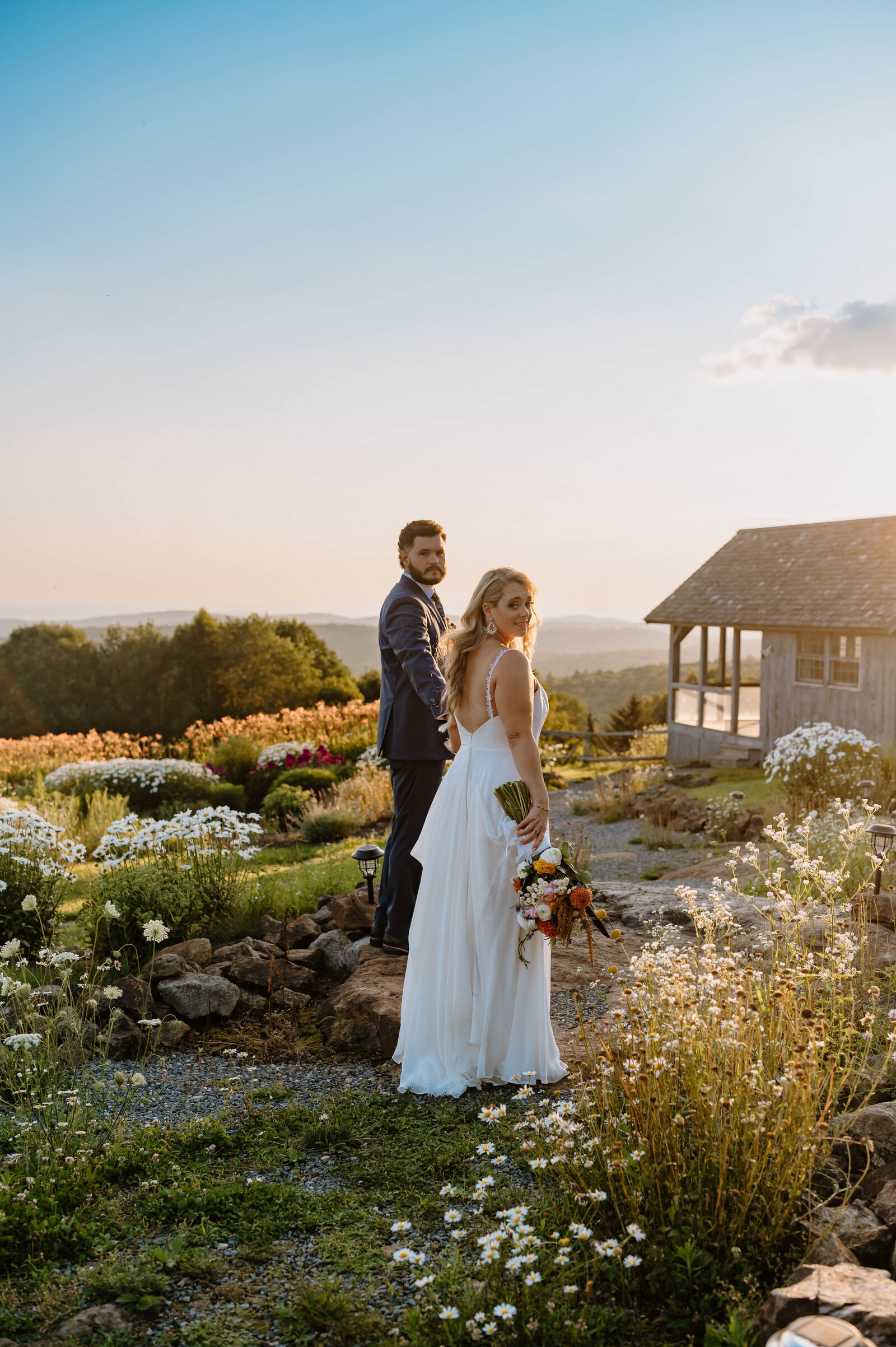 Bride and Groom standing together hand in hand in a flower field in New Hampshire