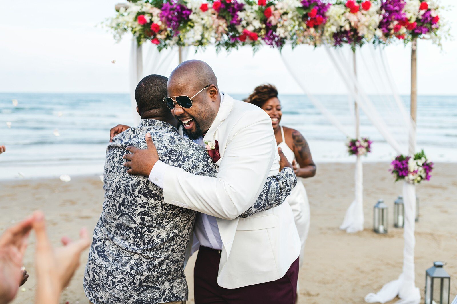 Groom hugging a guest at a beach wedding celebration