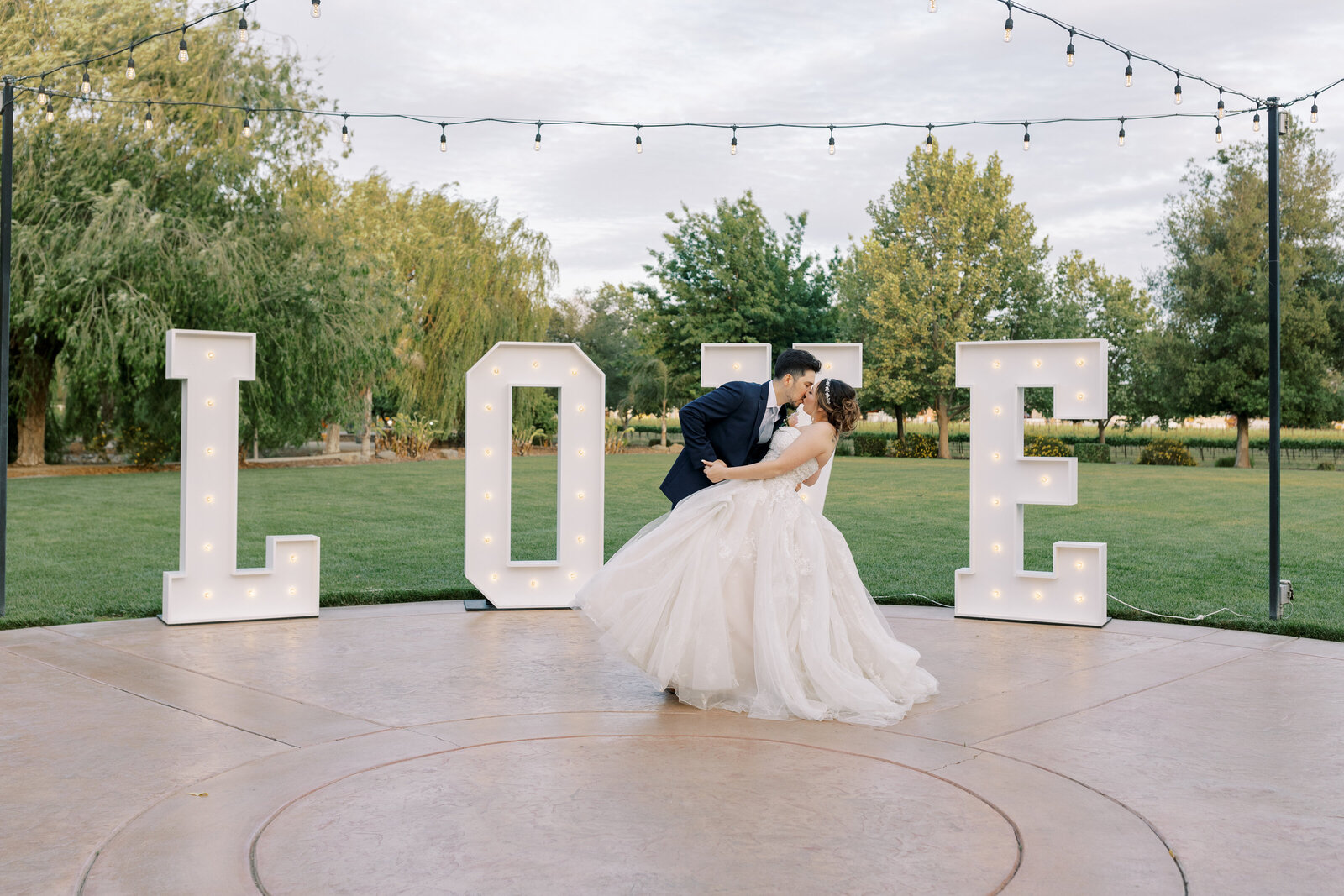 sacramento wedding photographer captures bride and groom dancing together and kissing on an outdoor dance floor patio at Wolfe Heights wedding venue in Sacramento