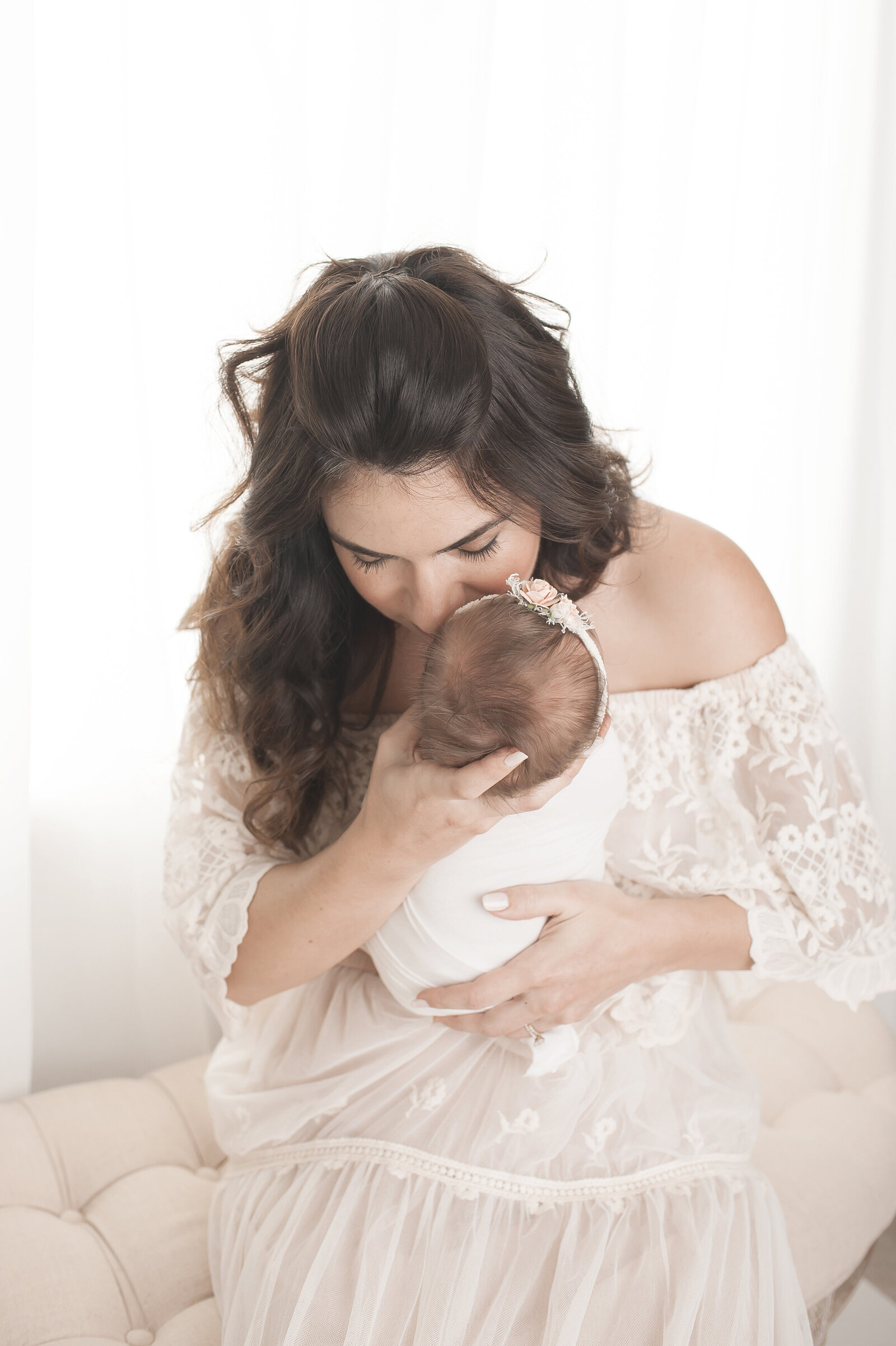 Mother in lace dress hugging newborn baby