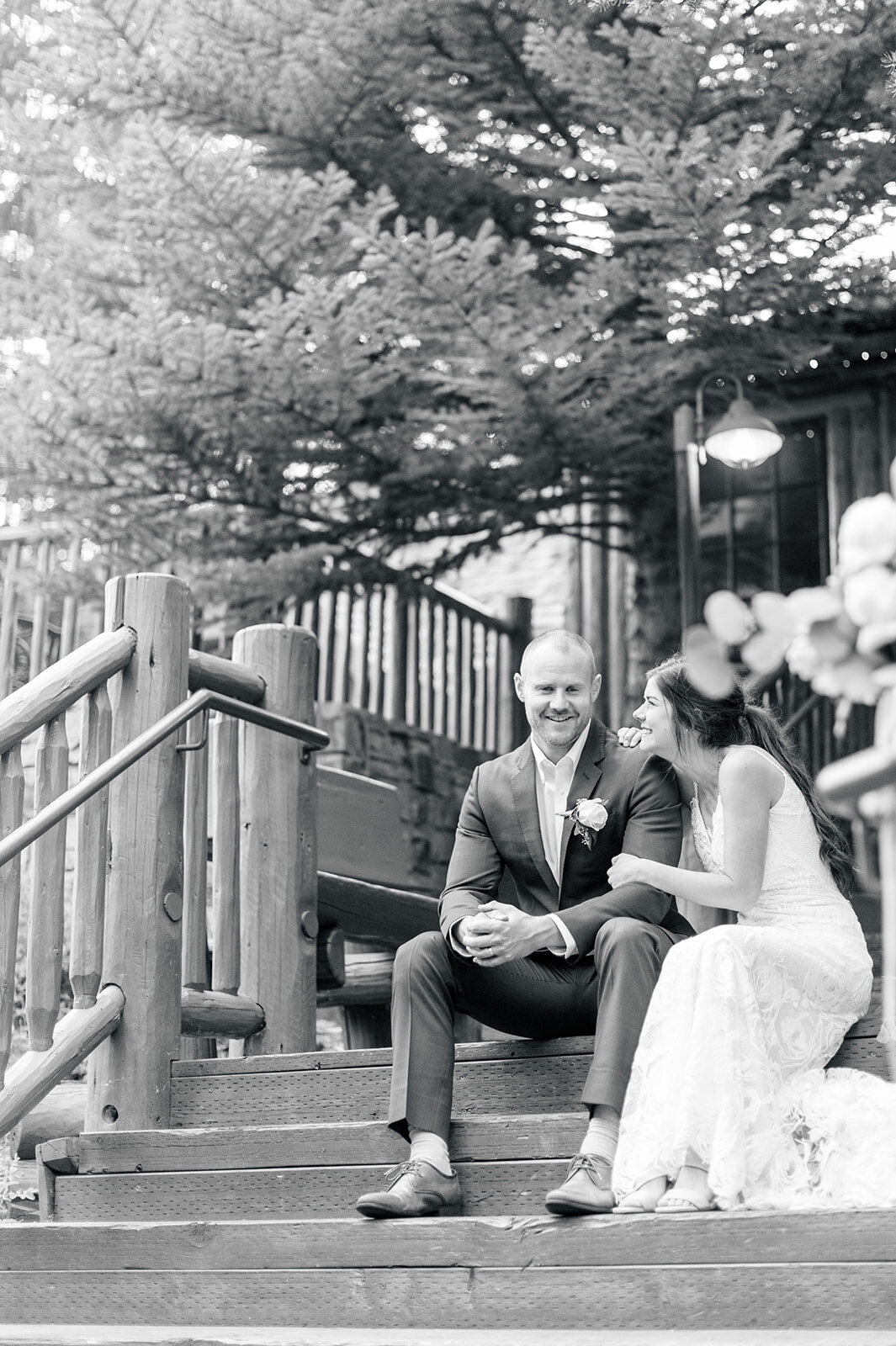 Bride and groom sitting on stairs at Trail Creek Cabin Wedding taken by the Best Sun Valley Wedding Photographers in black and white