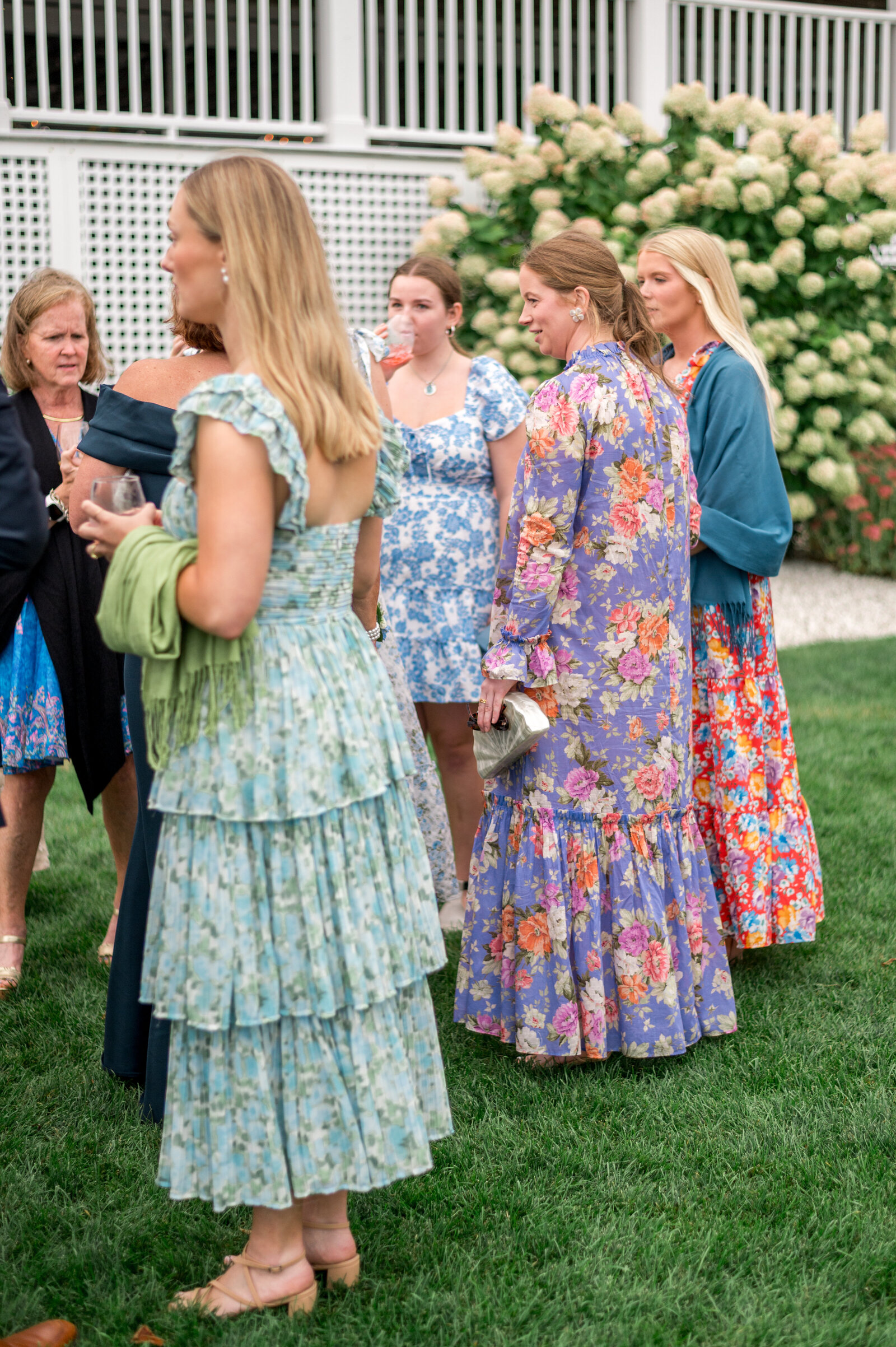 Wedding guests in colorful floral dresses during outdoor cocktail hour at Shining Tides Wedding — candid bright and airy wedding photography by Sarah Surette Photography.