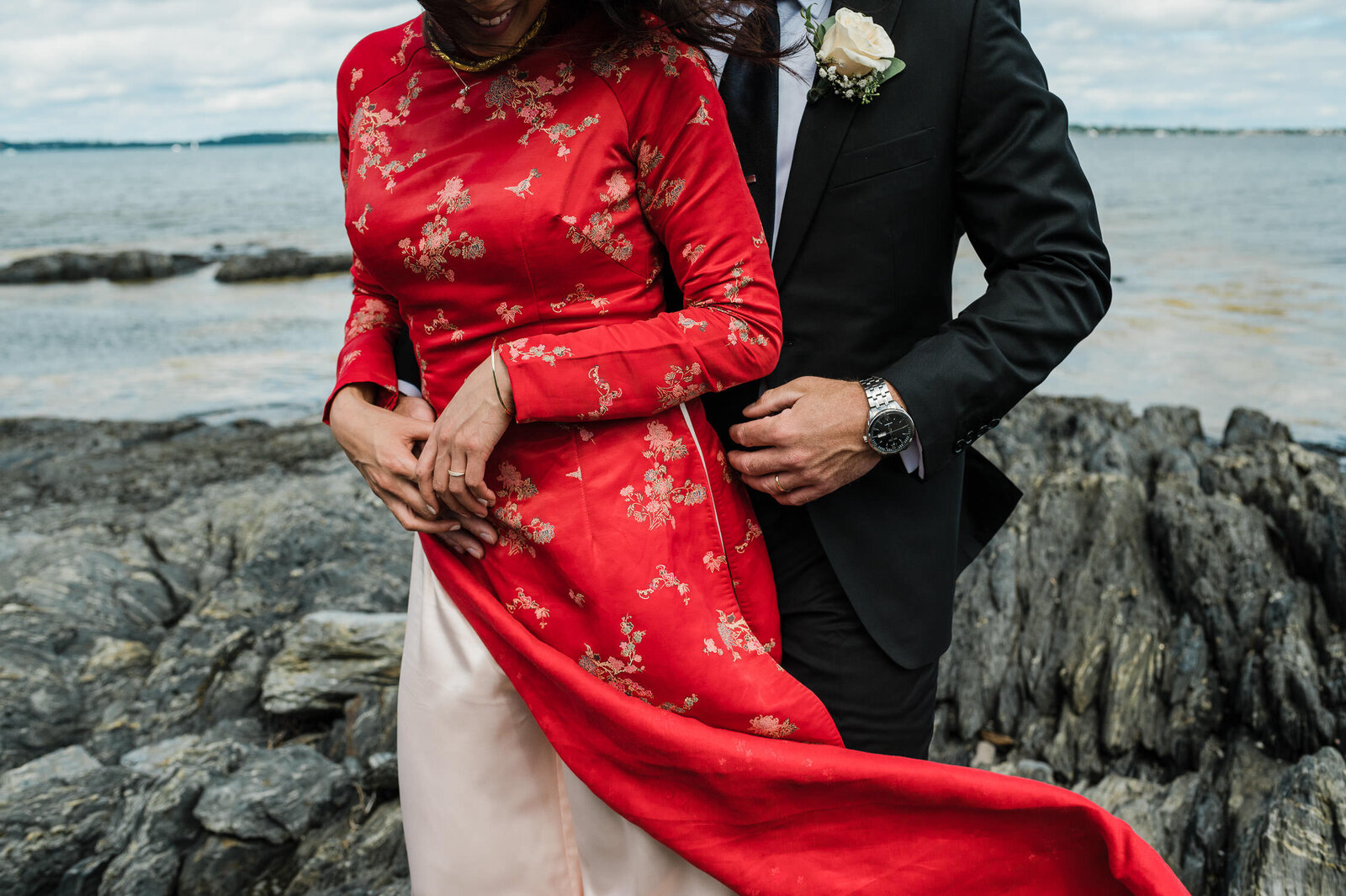 Closeup of wedding couple standing on rocky shoreline on a windy day in Nova Scotia.