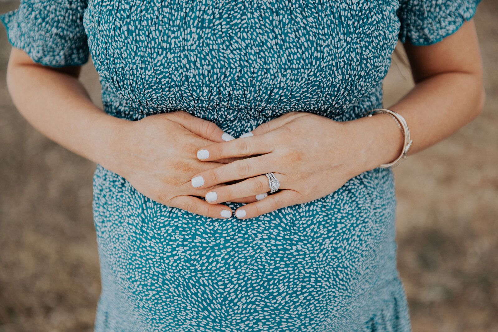 Idaho Falls maternity photographer documents the mothers baby bump while holding her hands over her tummy while wearing a blue dress