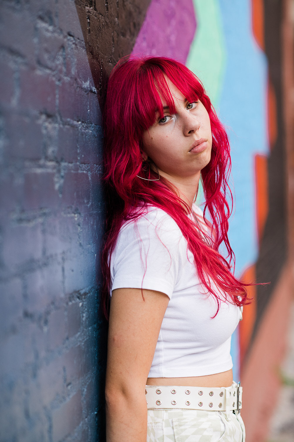 senior girl serious in front of colorful brick wall