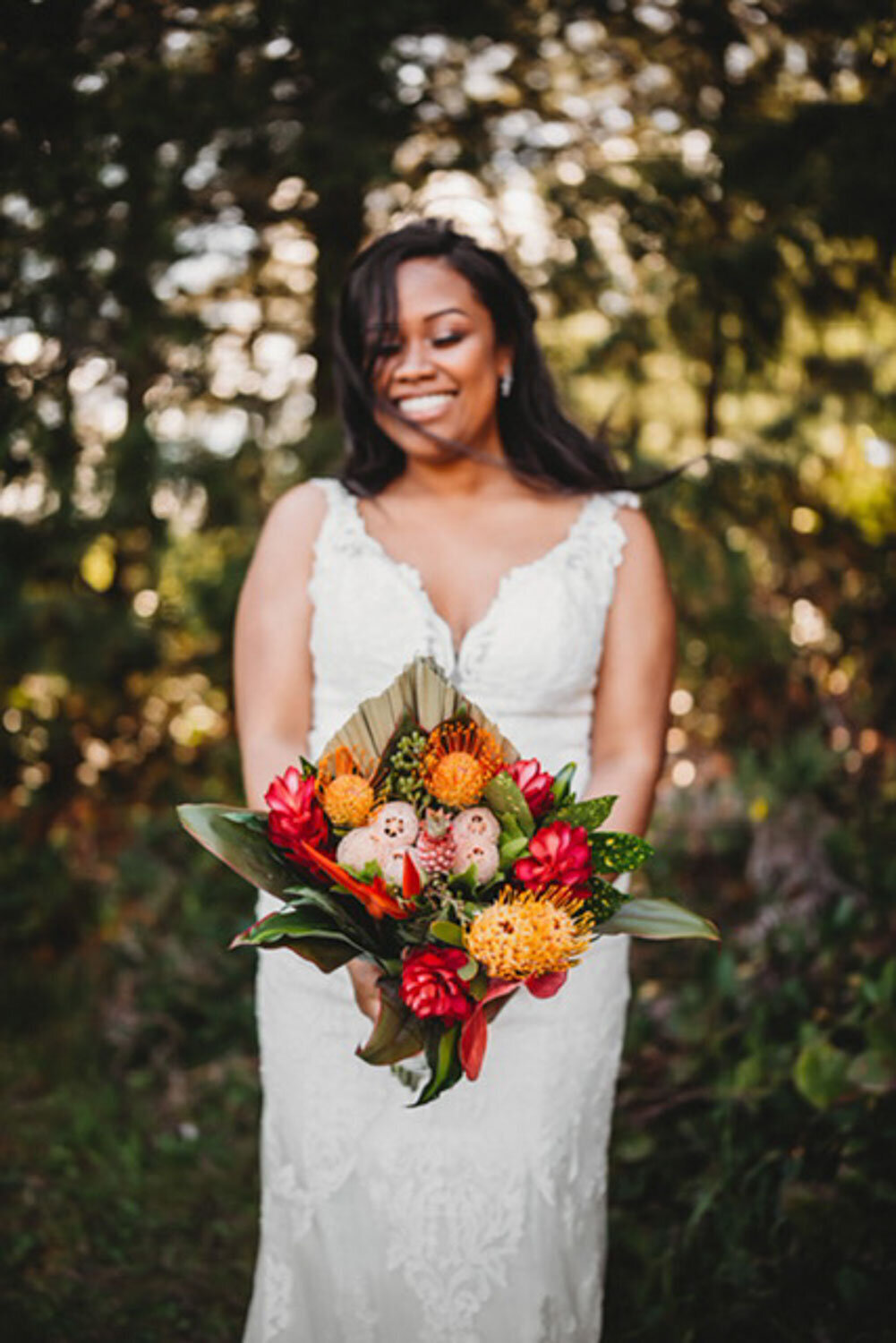 A bride holding a vibrant bouquet, standing in natural light