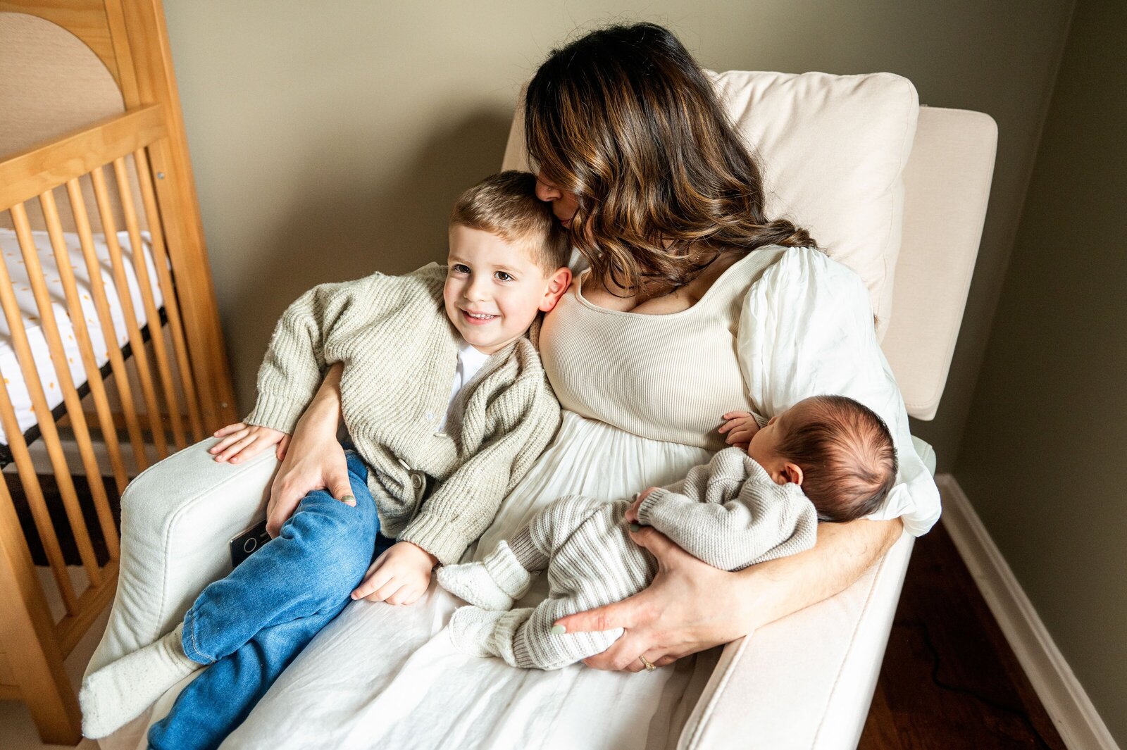 mom holding her two sons in her lap as newborn sleeps