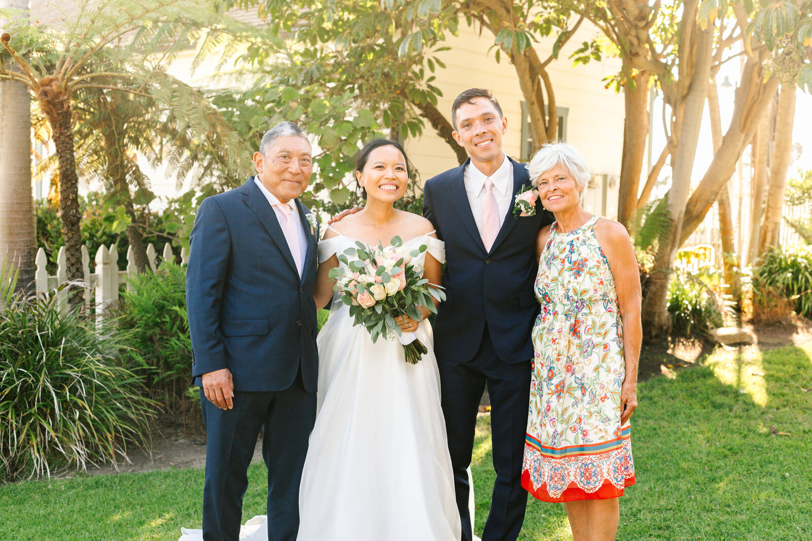 A bride and groom pose with the mother and father of the groom after their wedding ceremony.