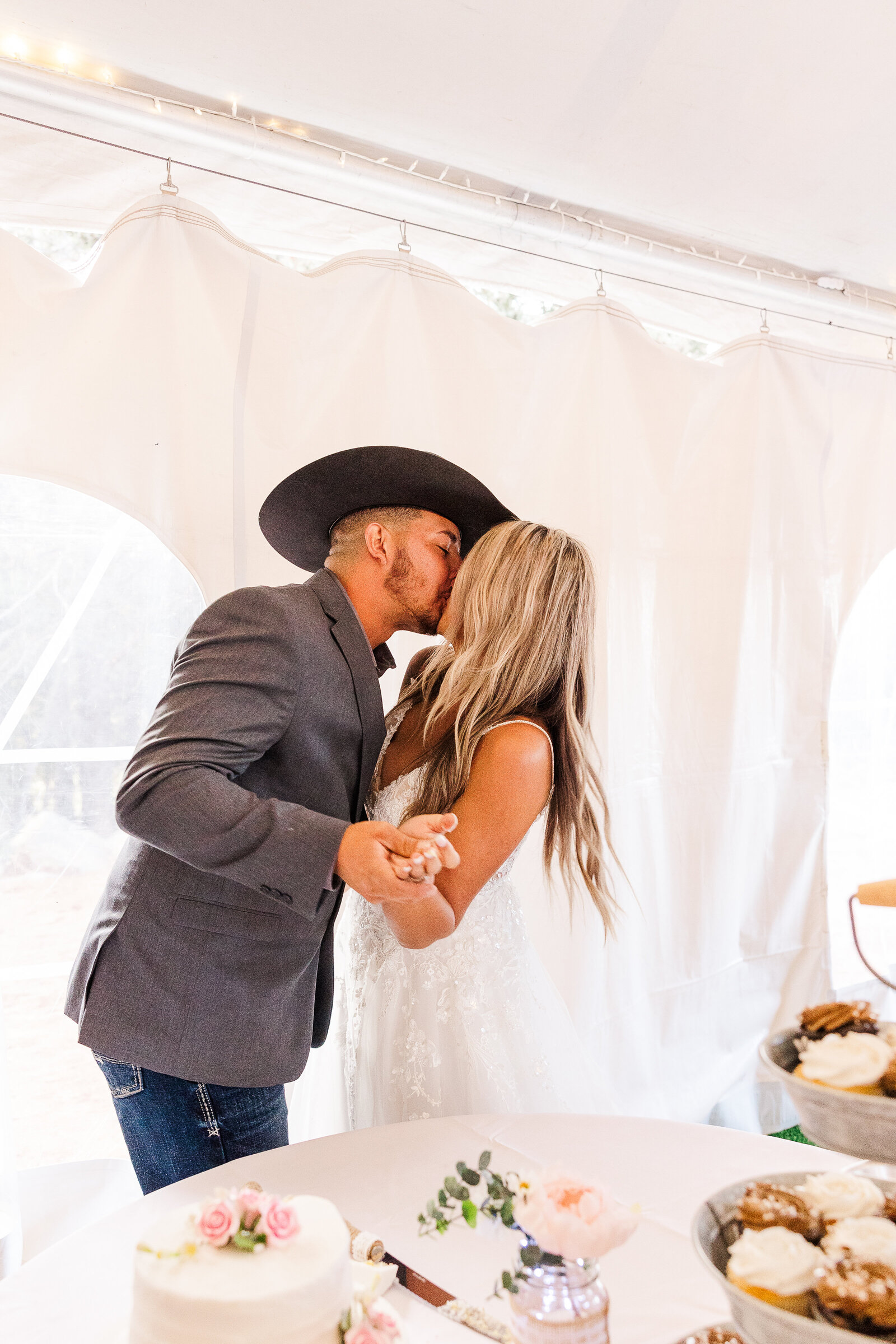 Newlyweds share a romantic kiss over their wedding cake at Arrowhead Mountain Lodge