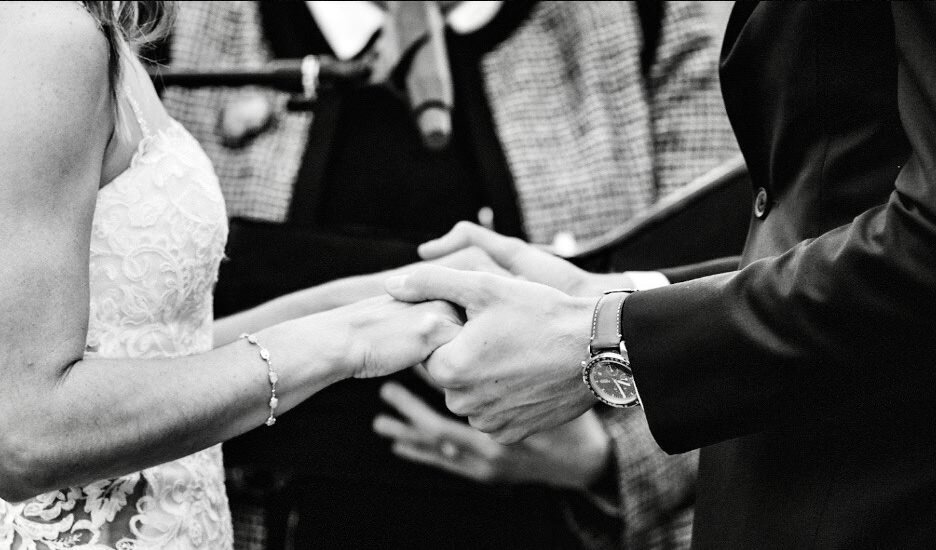 Close up of bride and groom holding hands during wedding ceremony