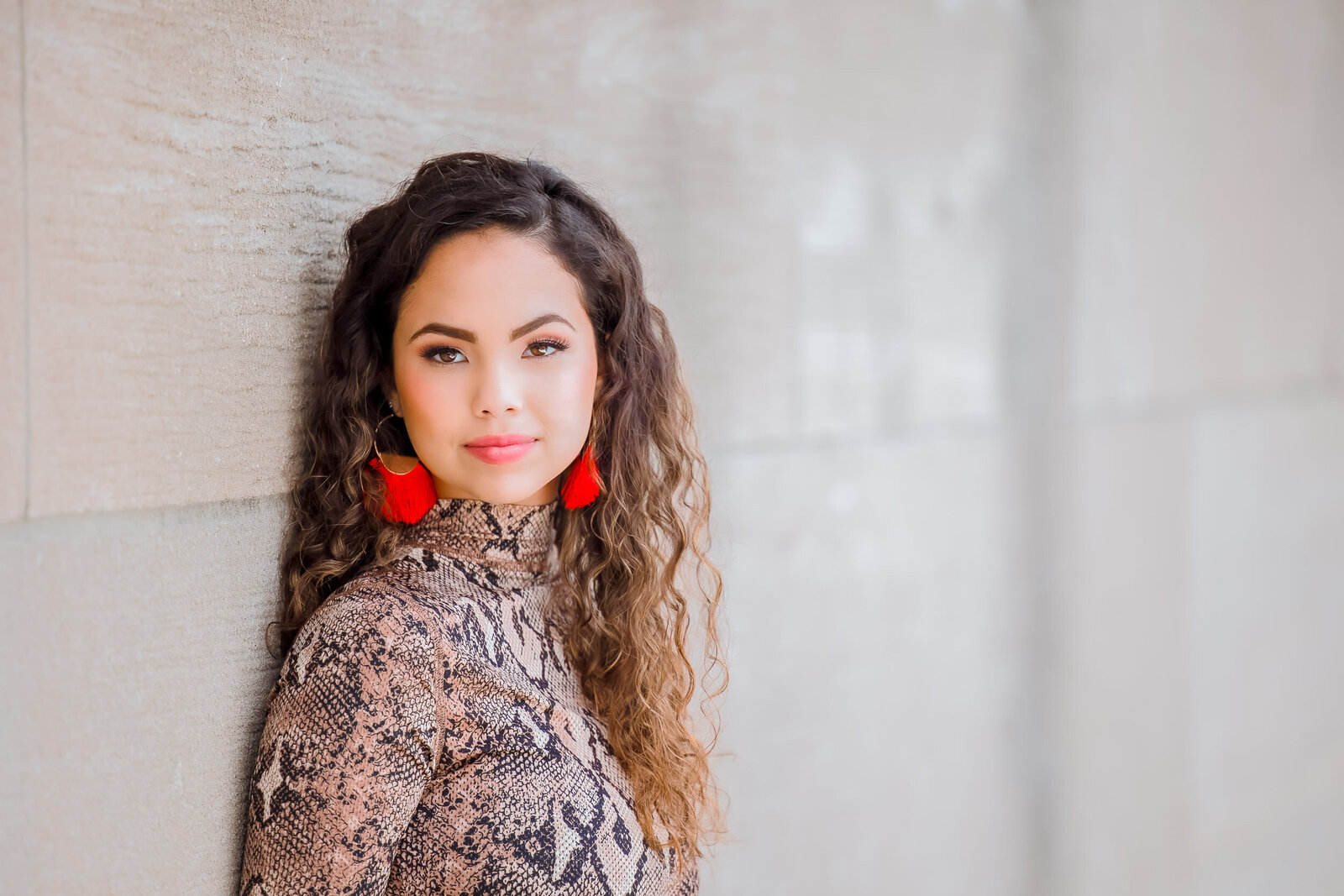 brunette senior girl with curly hair and red earrings in a close up downtown Kansas City