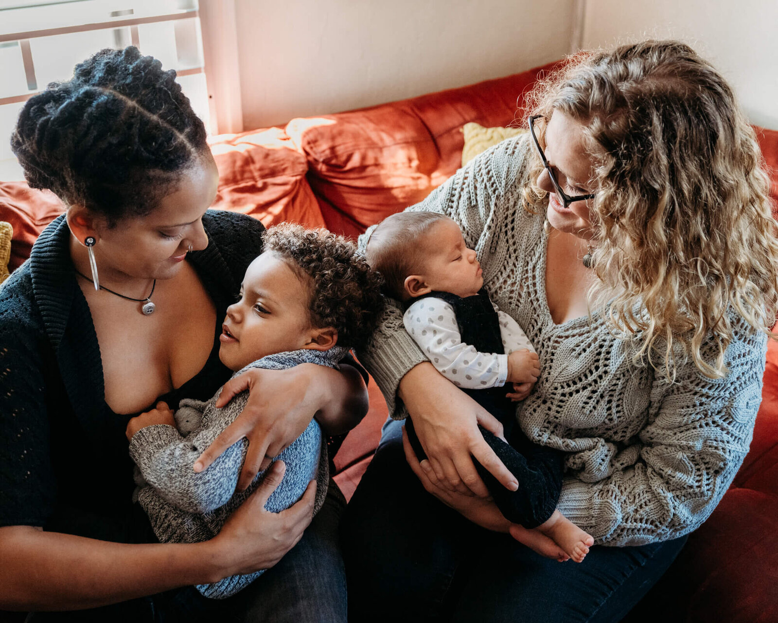 Moms cuddle their two kids during in home newborn photo session